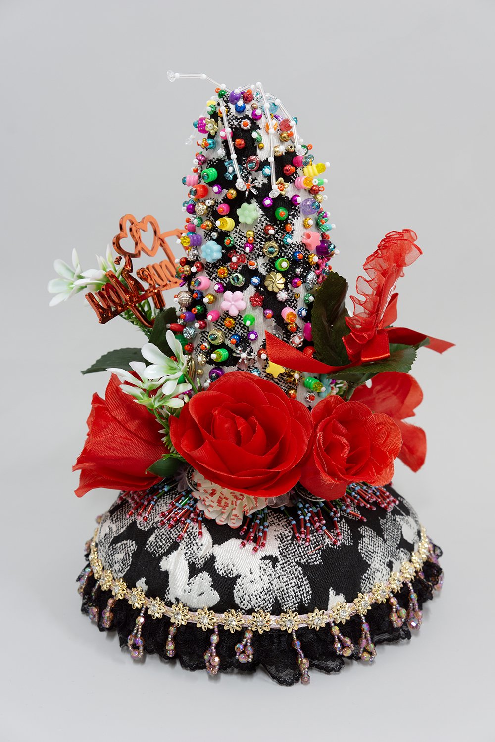   Untitled,  2024, Plastic beads, found fabric, trim, fabric and plastic flowers, buttons, plastic and polyester picks, polyester batting, thread, 12.5 x 9.5 x 9.5” 