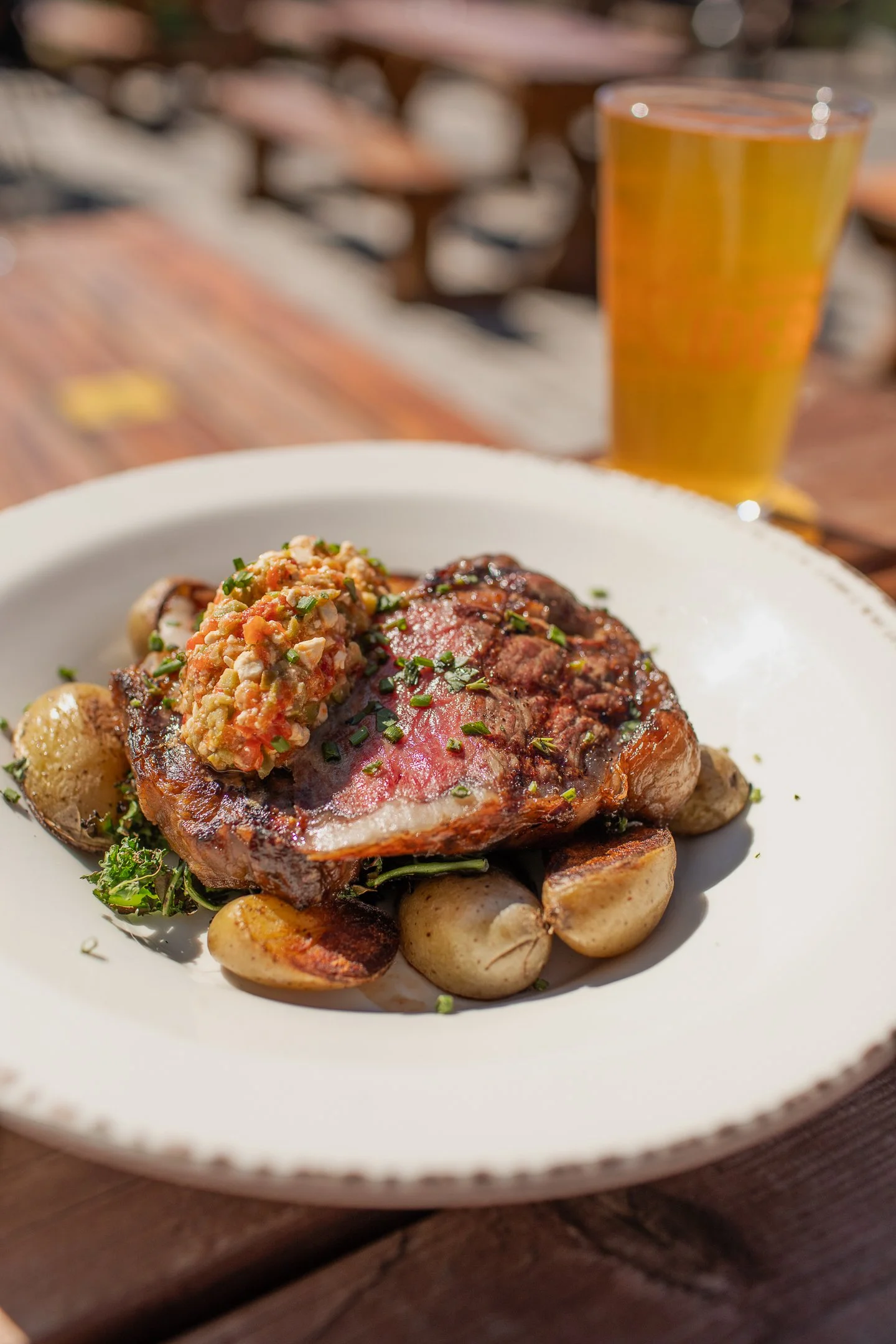 A perfectly cooked steak and potatoes an a plate outside on a restaurant table