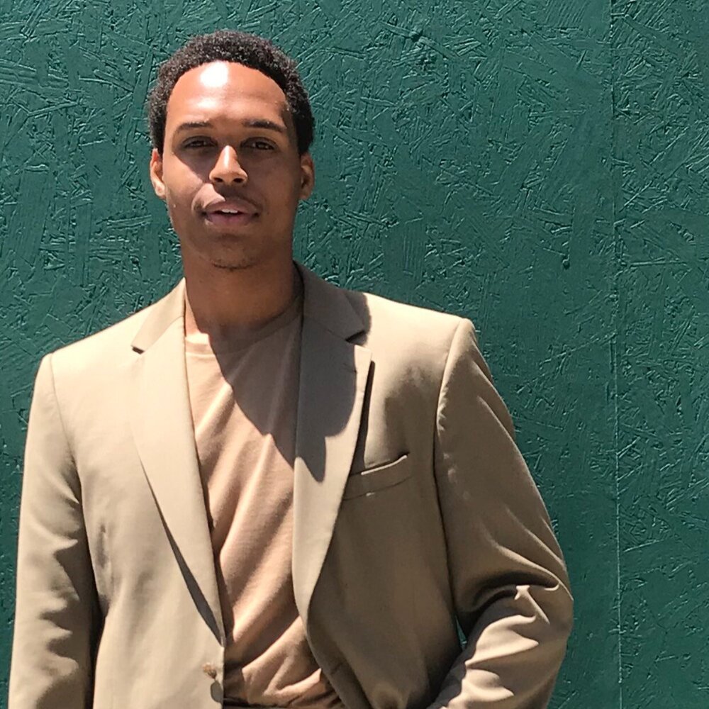 student standing in front of green wall