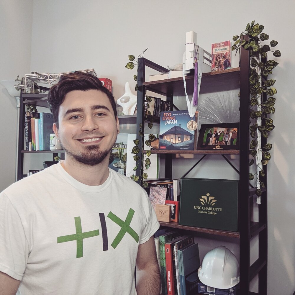 student smiling in front of his diploma 