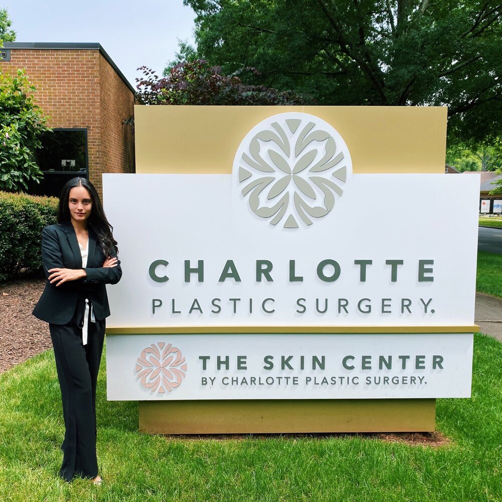 student standing with plastic surgery sign