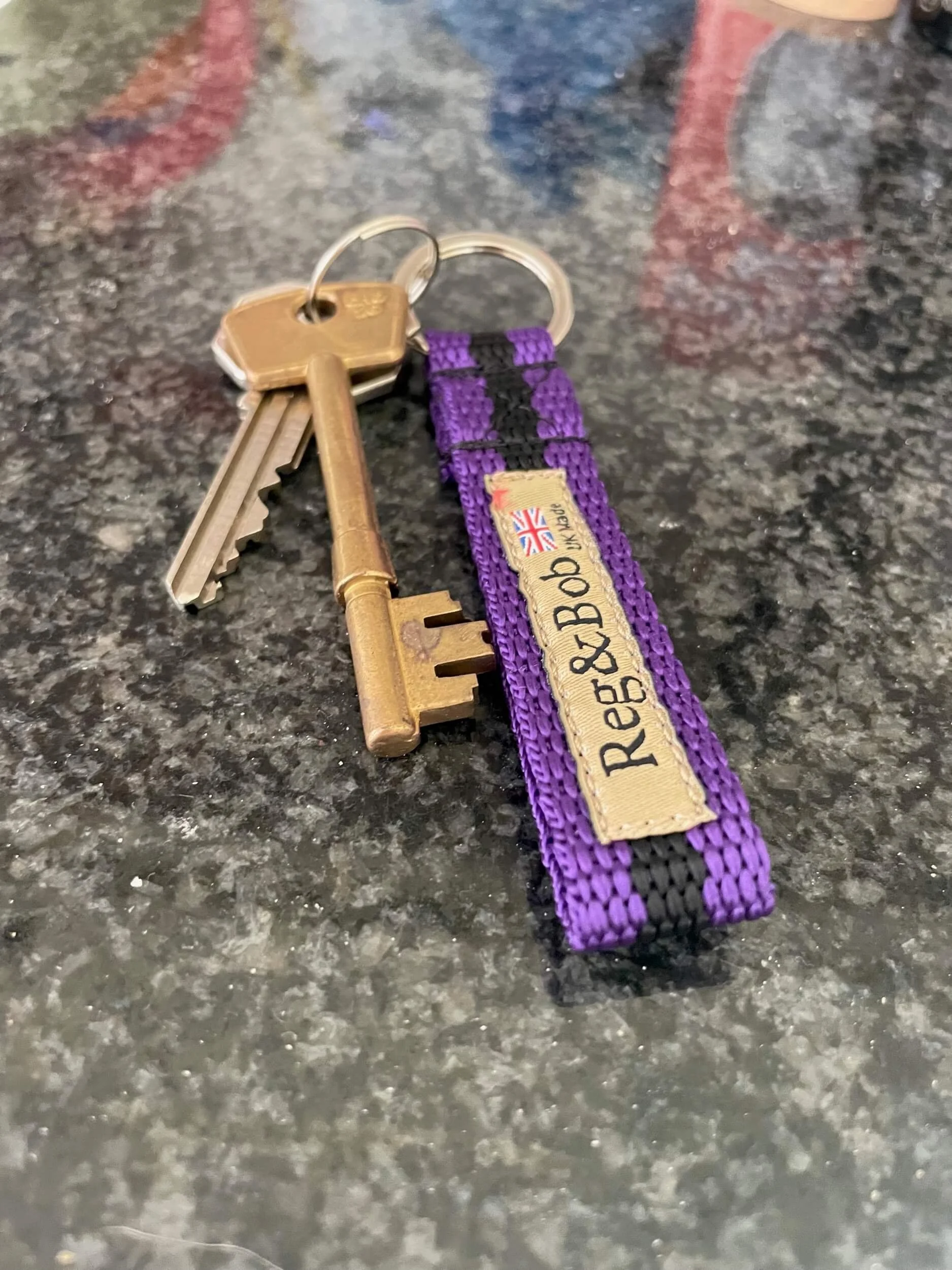 purple striped keyring by Reg&Bob with keys attached sitting on granite work surface