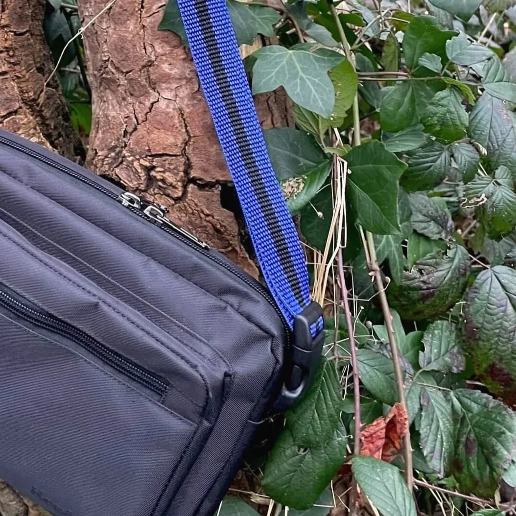 Close up of black crossbody Reg&Bob dog walking bag with blue strap