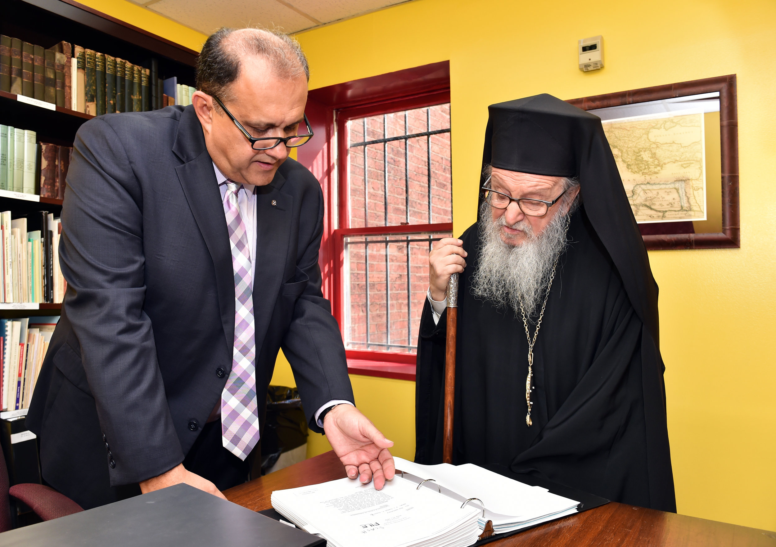  Nick Larigakis shows His Eminence Archbishop Demetrios of America an example of the thirty one volume set of declassified documents on the Cyprus invasion of 1974, compiled by Gregory Graves. 