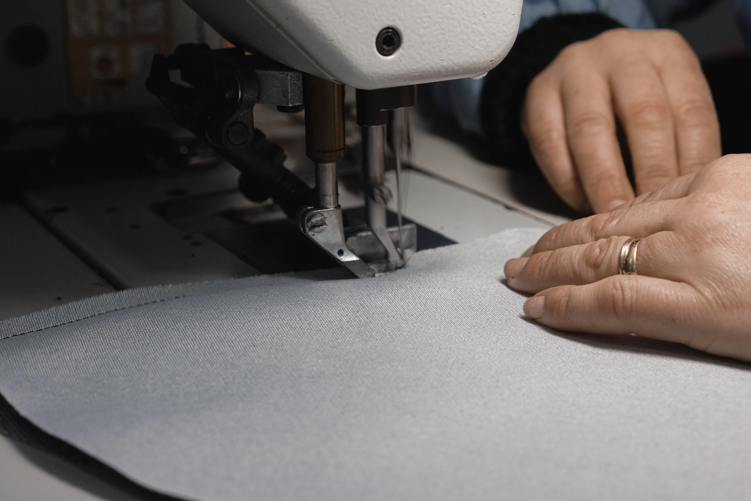Close-up of hands guiding fabric through a sewing machine in a sewing workshop.