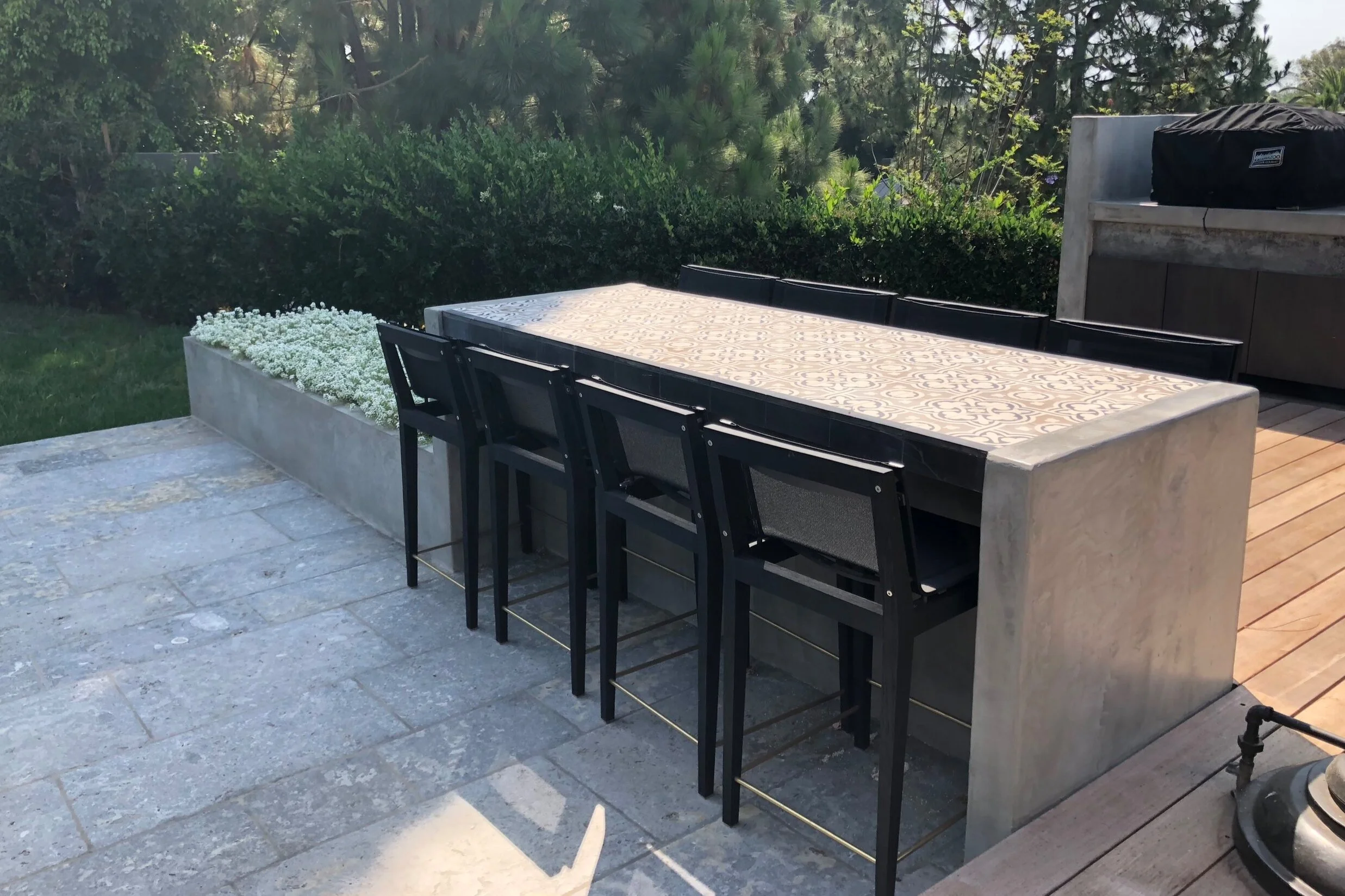  The concrete table topped with cement tile is hugged by the wood deck. 