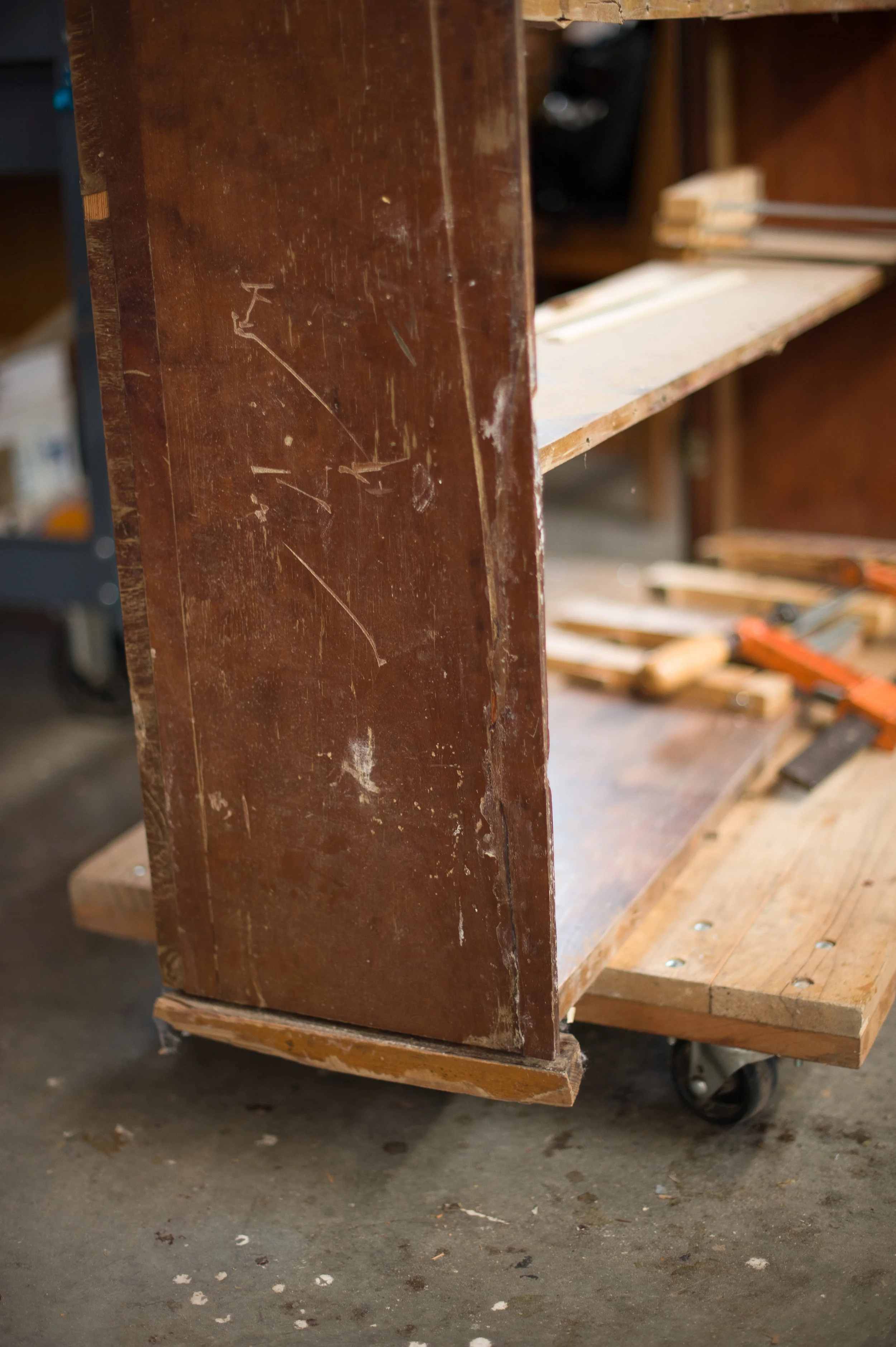Gouges and scratches in the bookcase side panel. Note the damaged plinth along bottom edge. The mahogany on the plinth is of an inferior quality and likely a restoration.