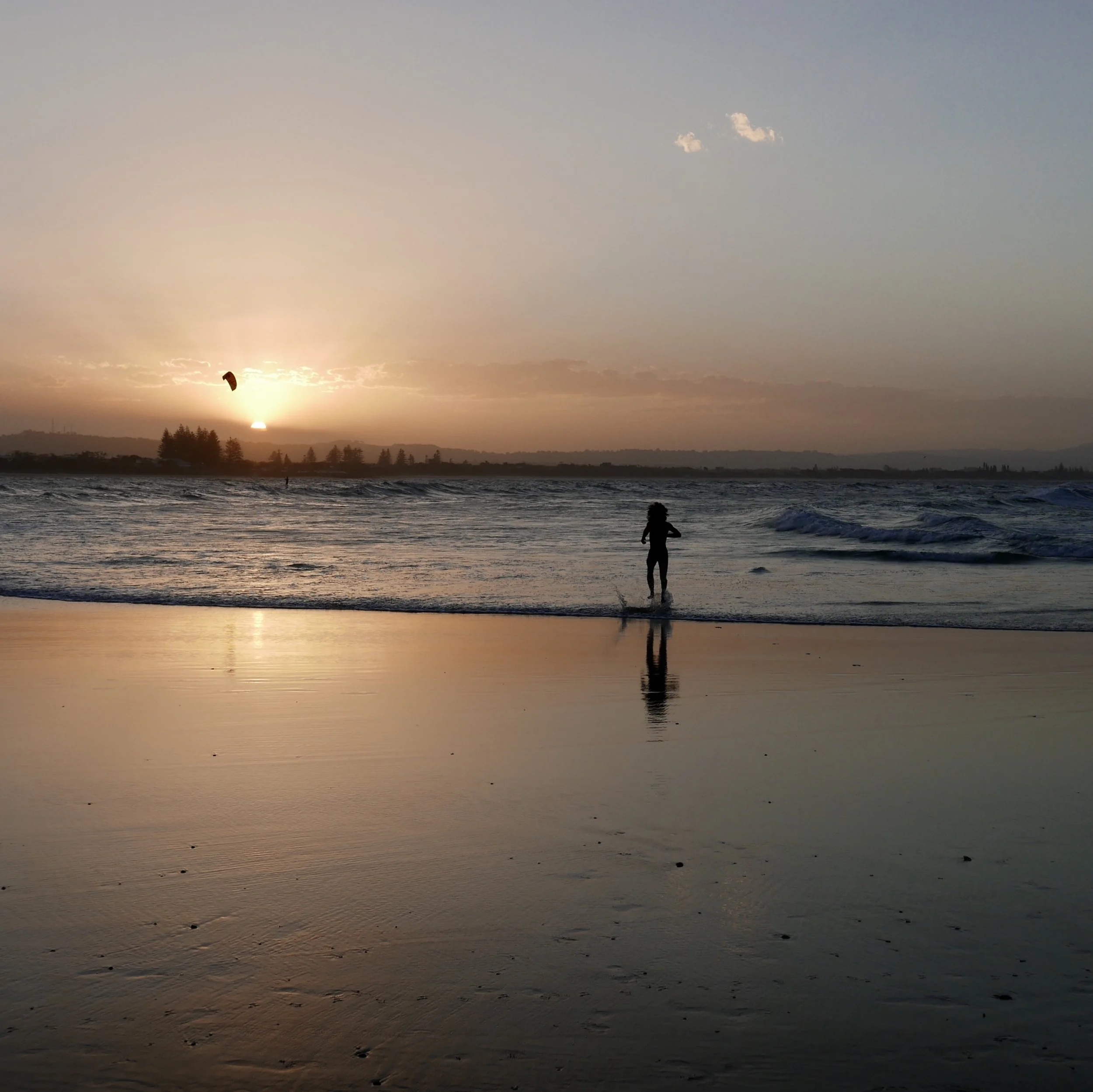 Classic Byron Bay. Sunset, surf, surfers and kite surfers and this man running in for one last swim as the sun sets. This beach, The Pass, is incredibly popular and guarantees fabulous people watching too.