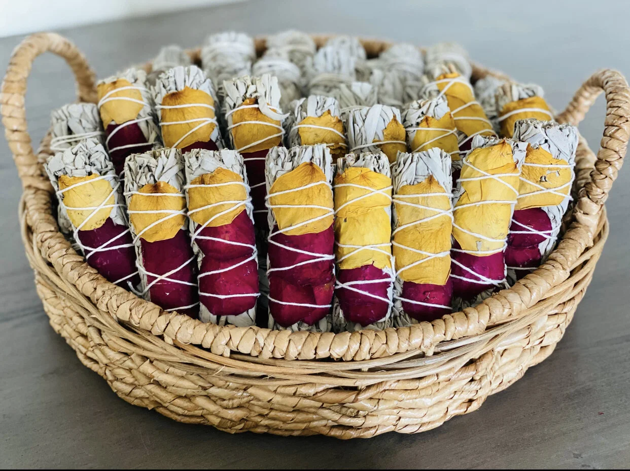 bundles of sage with colorful petals in a basket