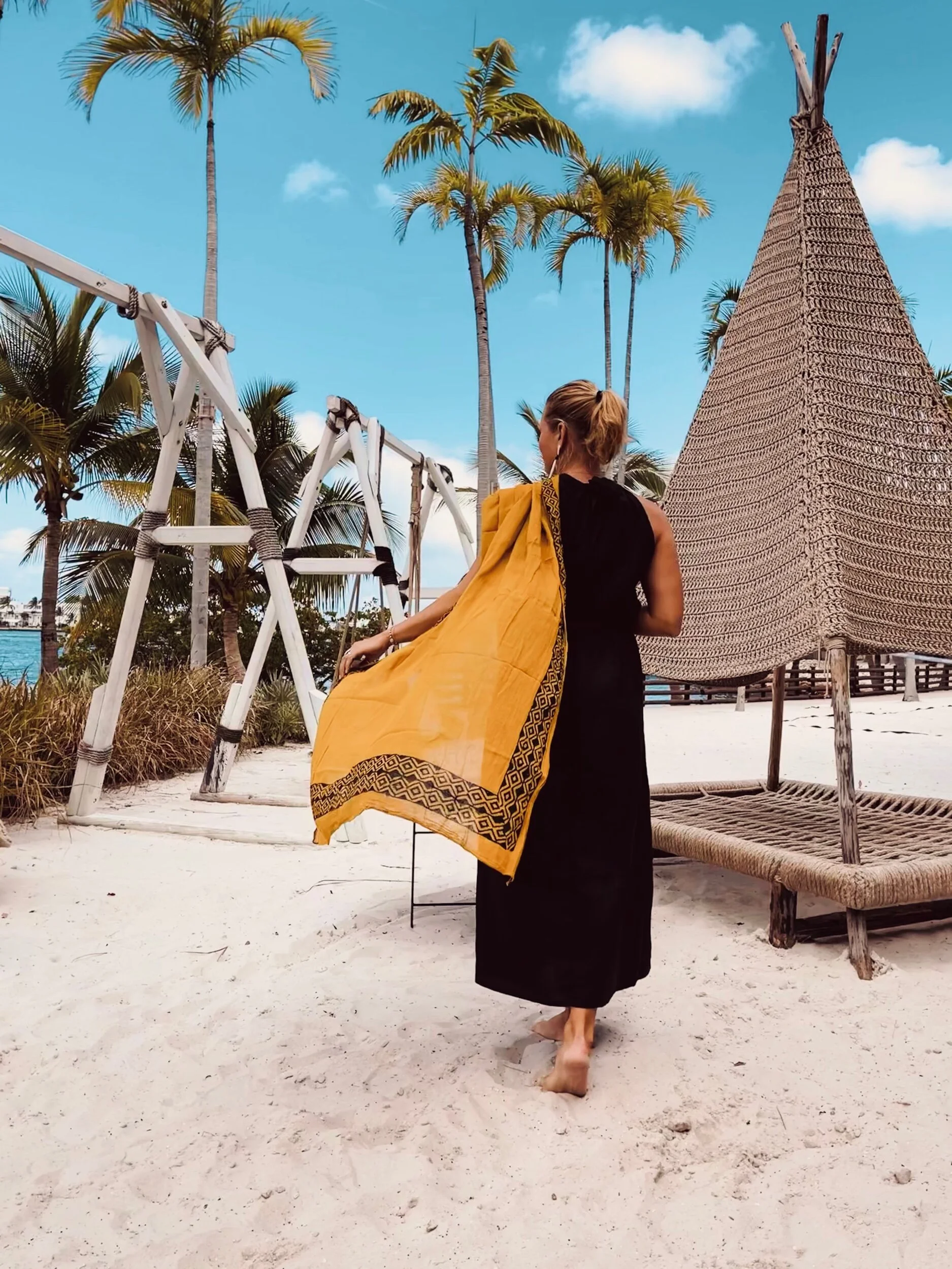 Woman holding pareo facing away from camera.