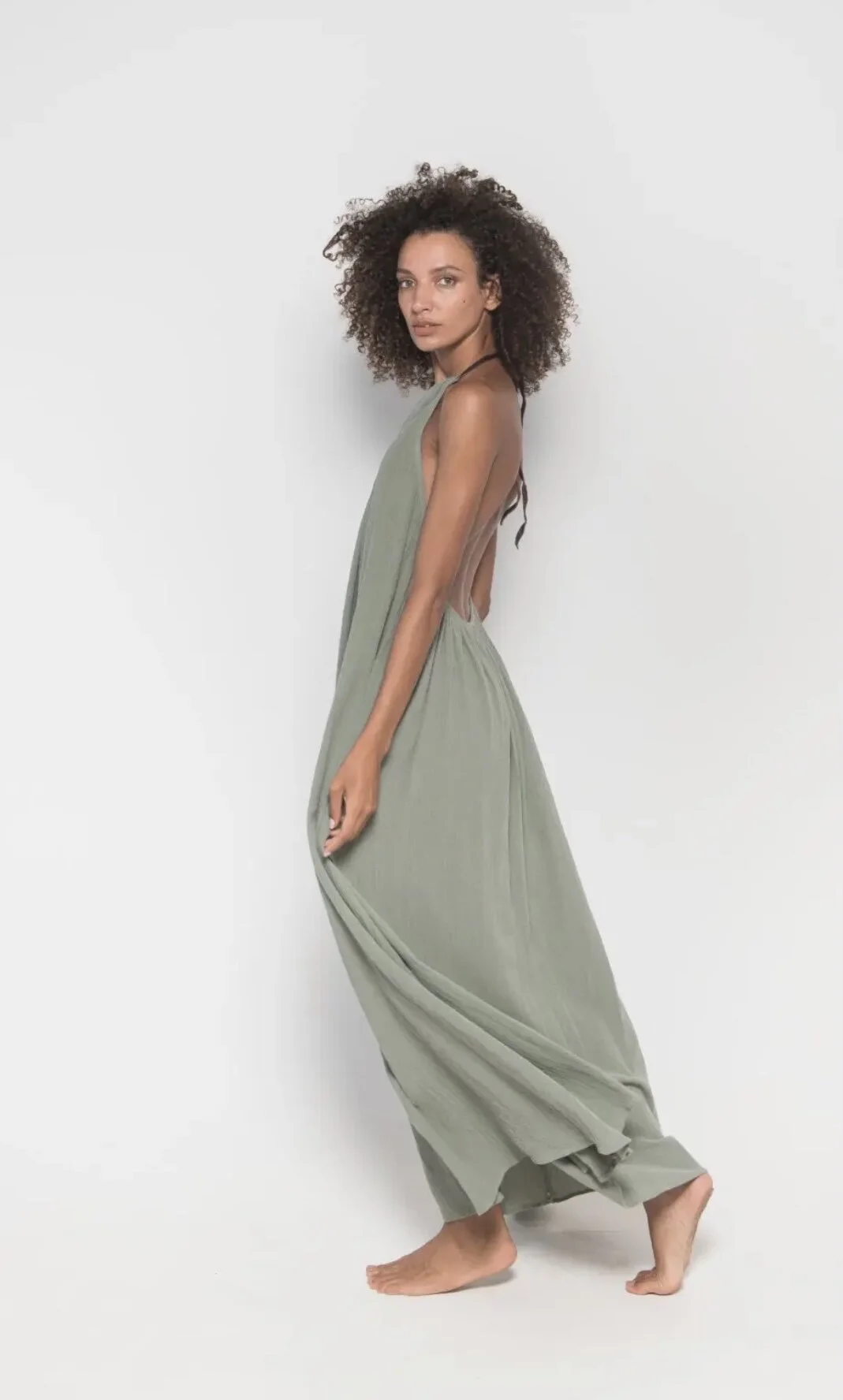 Woman wearing green maxi dress on white background in Brickell Center.