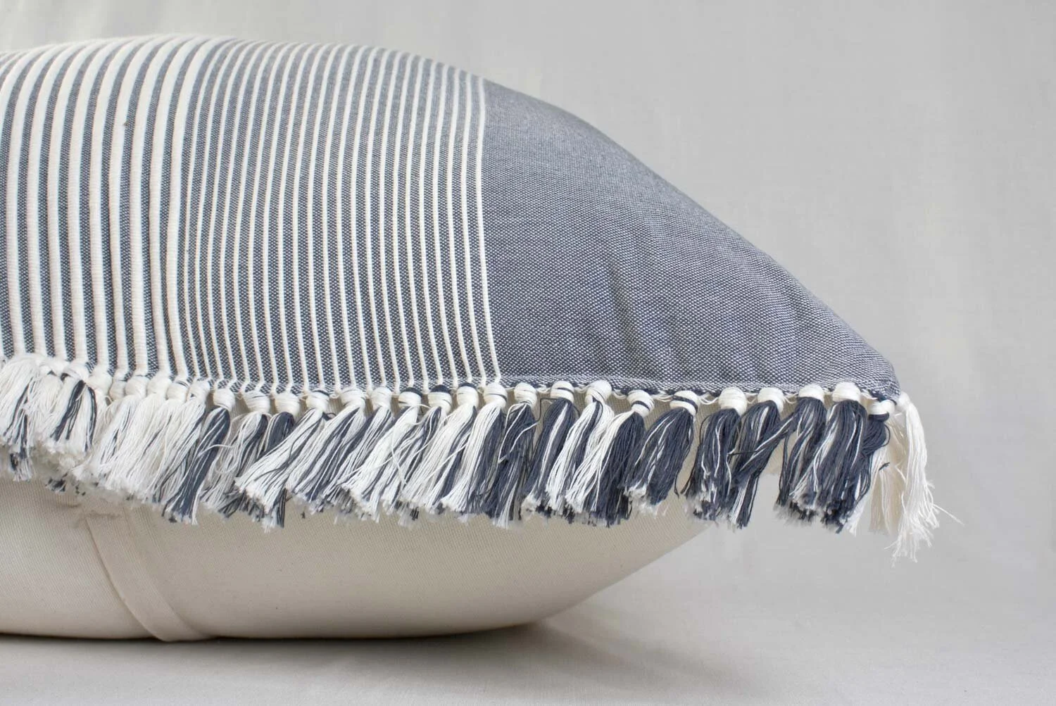 Grey and white striped pillow on white background.