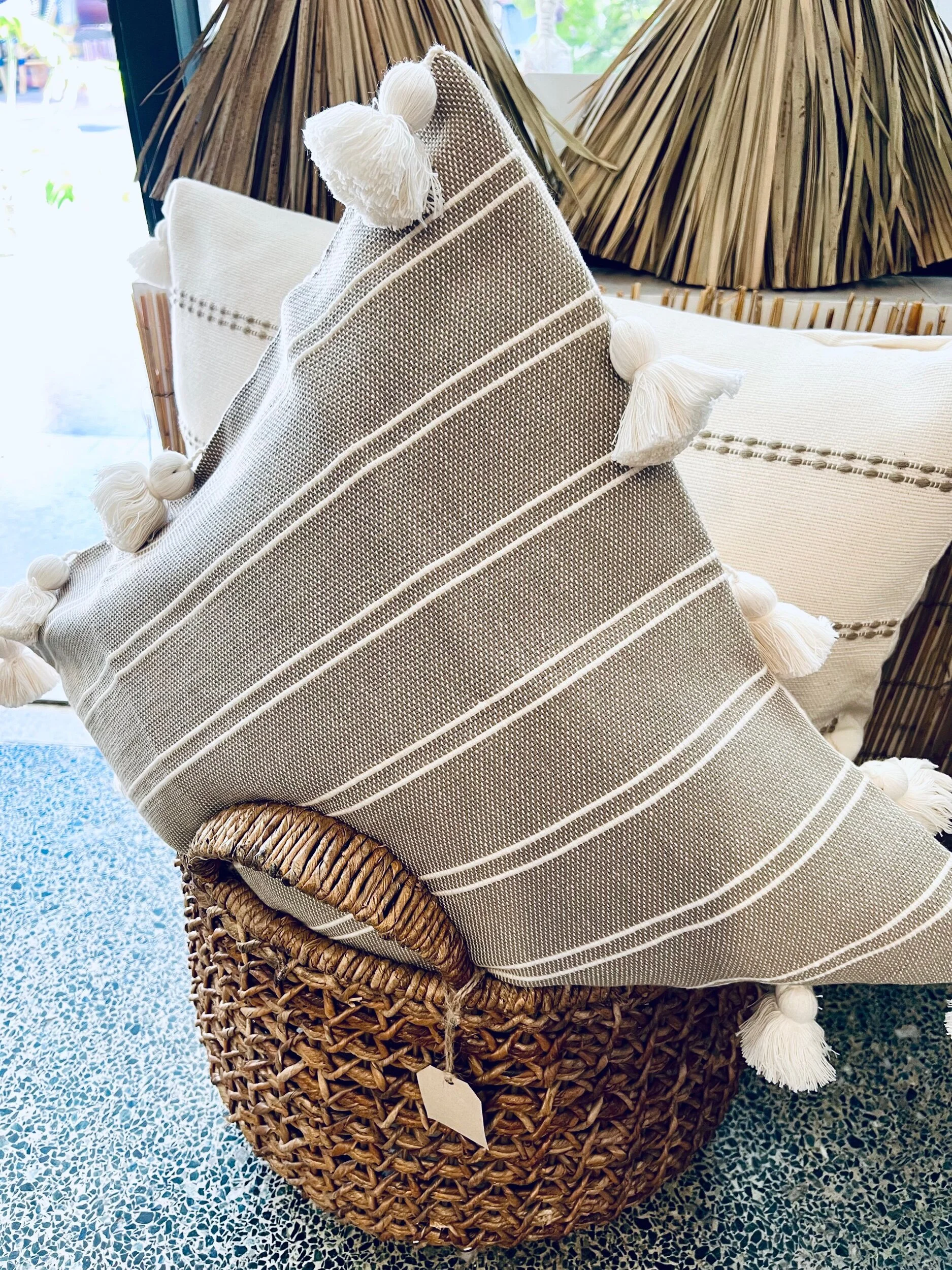 Striped grey square pillow with white tassles.