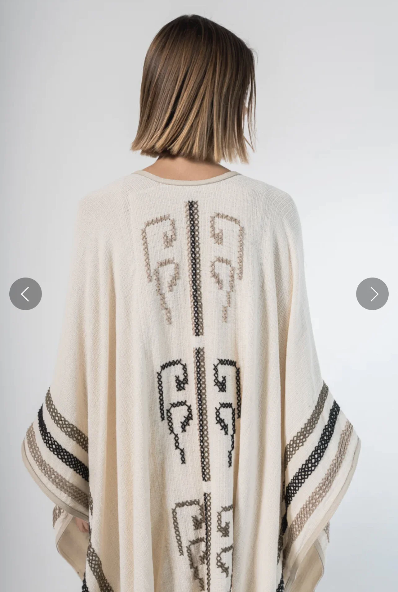 Woman facing away from camera wearing punta cruz poncho.