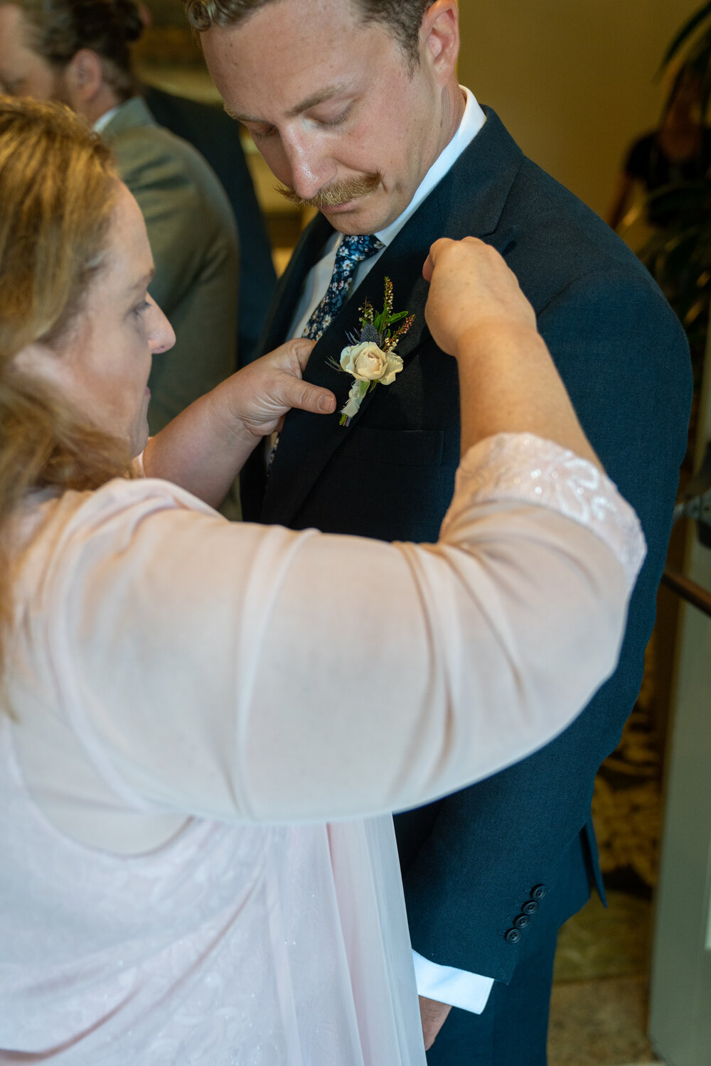 Mom helps the groom with his boutonnière.