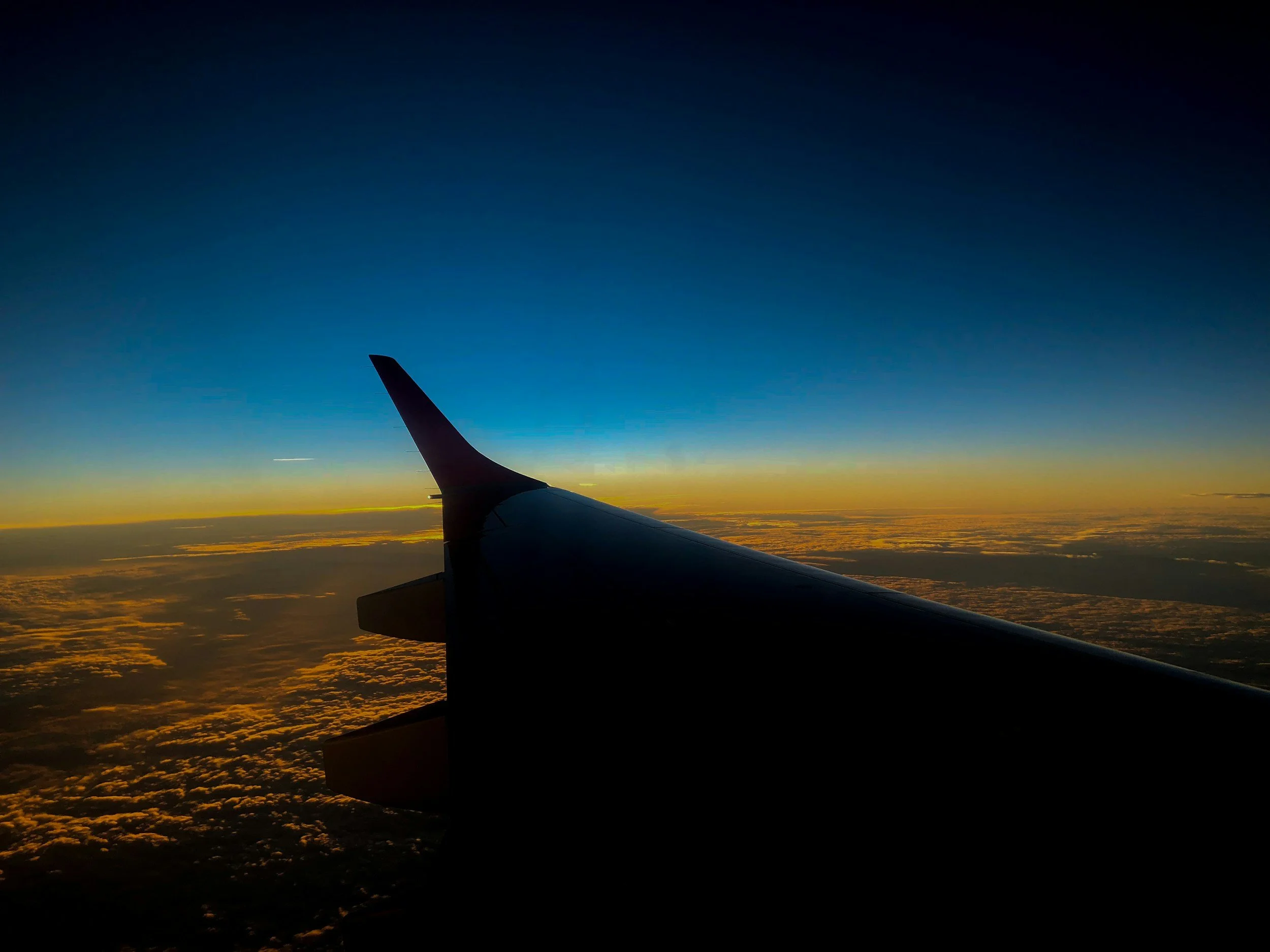 Vista de la cola de un avión y el cielo durante el atardecer desde la ventana del avión.
