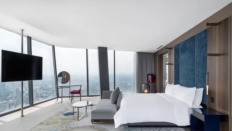 Vista aérea de un campo de golf con hoyos y un lago, rodeado de árboles y vegetación, bajo un cielo parcialmente nublado.