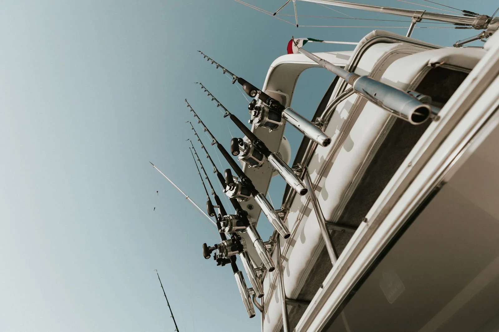 Varios cañeros de pesca montados en la parte superior de un barco contra un cielo despejado.