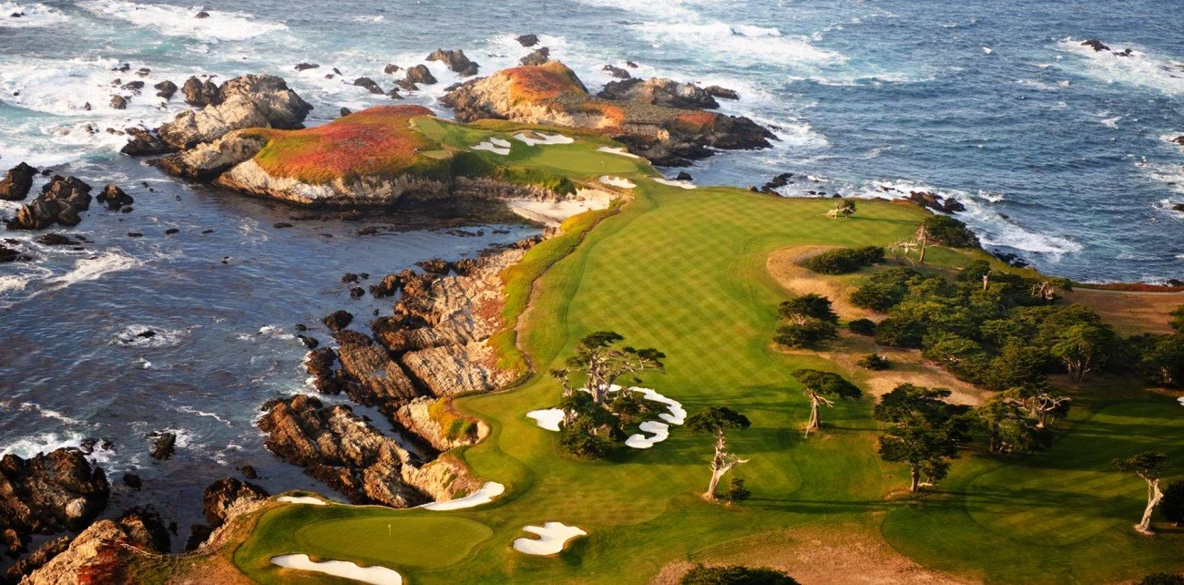 Vista aérea de un campo de golf junto al océano con áreas de arena, rocas y vegetación.