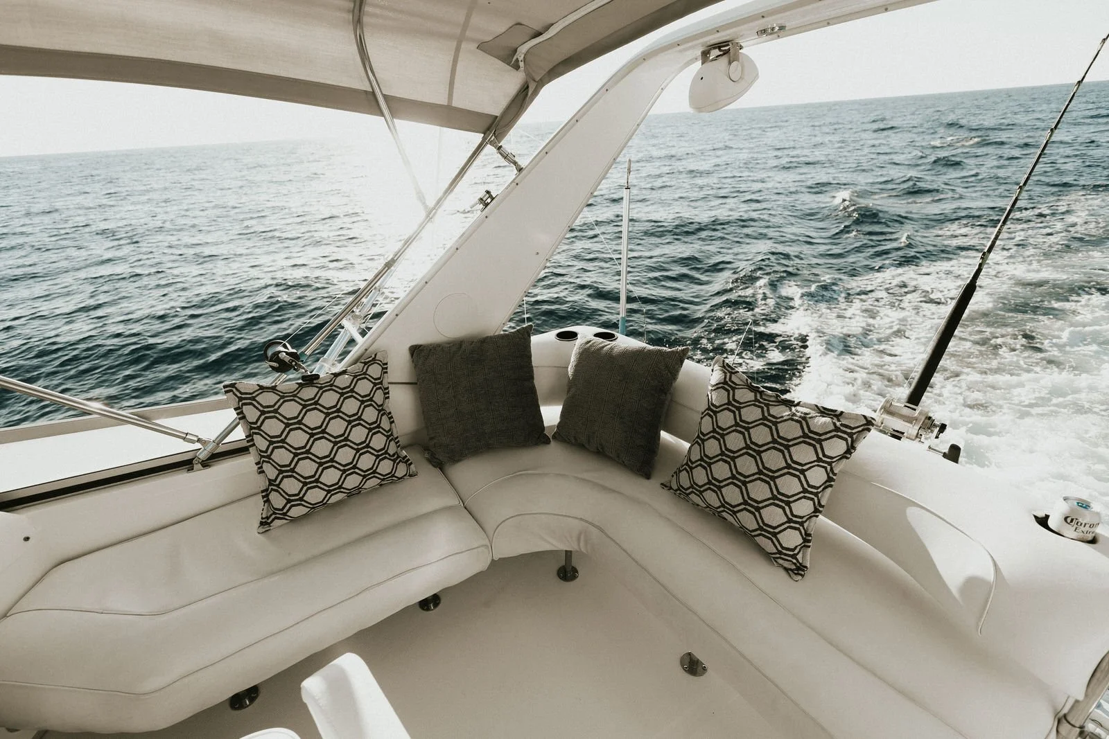 Vista del interior de una lancha con cojines grises y blancos, y vista del mar en el fondo.