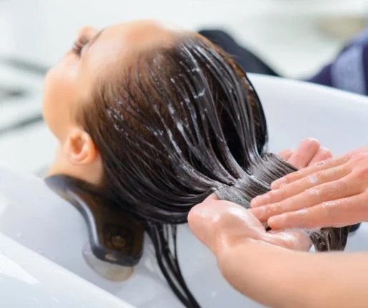 stylist is applying hydrating Hair Masque to woman's Hair