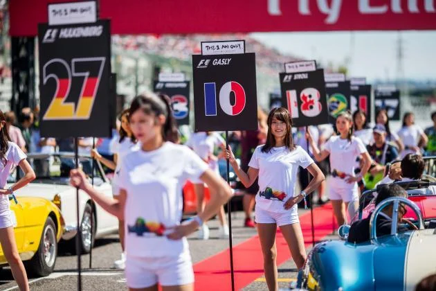 “Grid girls” holding driver name boards during a Formula One race.(Photo Credit: TalkSport)