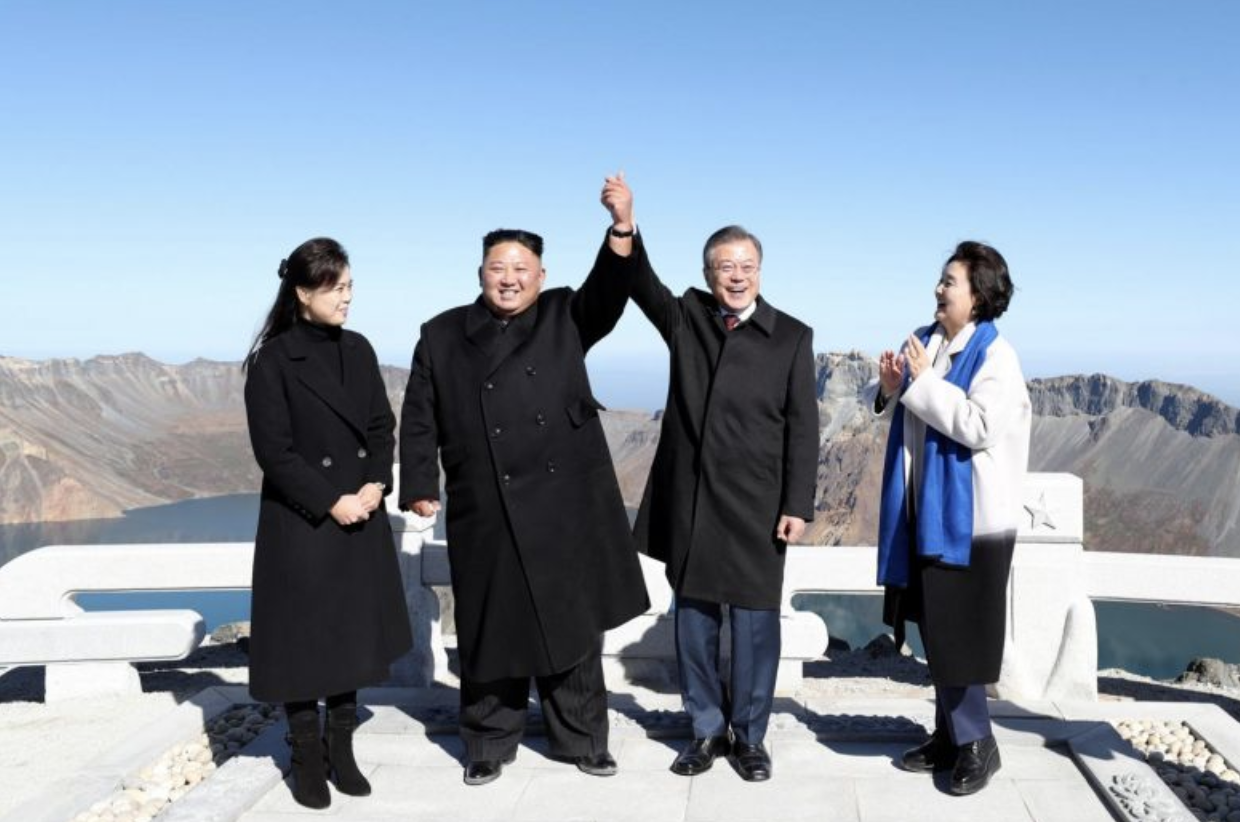 DPRK Chairman Kim Jong-un (second from left) and ROK President Moon Jae-in (second from right) raise their joined hands as Ri Sol-ju (first from left) — wife of Chairman Kim — and Kim Jung-sook (first from right) — wife of ROK President Moon — look on at the summit of Mount Baekdu in the DPRK on Sept. 20, 2018. (Photo: Reuters