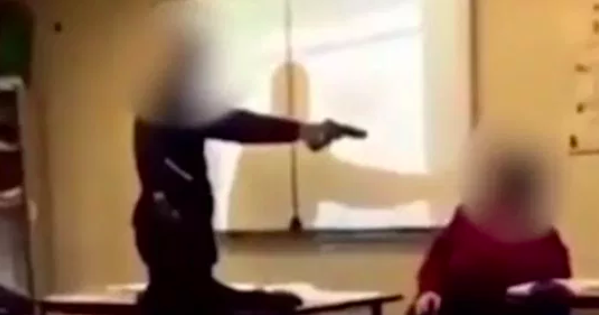 A high school student in Creteil, France threatens his teacher with a fake gun. Photo: Metro