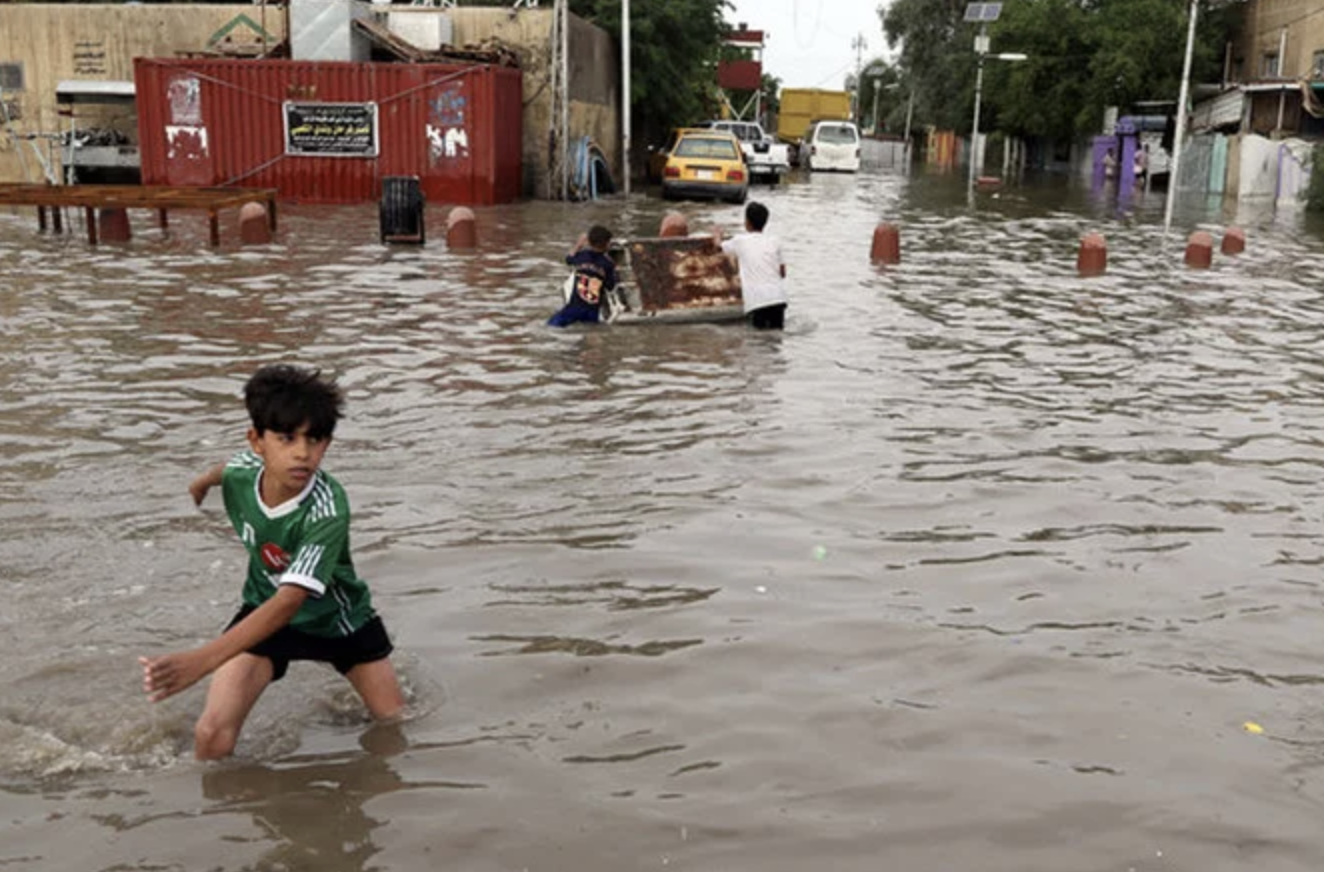 A boy walks through a flooded area of Baghdad, Iraq. Credit : Associated Press