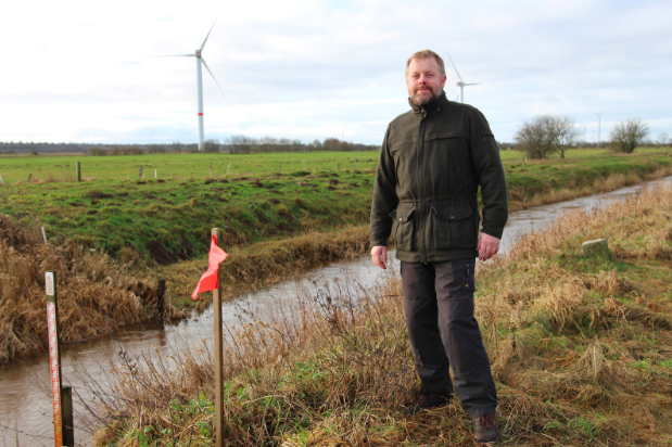 Hans Kristensen, a Danish hunter and forest engineer, stands alongside a flag marking the path of Denmark’s planned border fence. Photo: Sidsel Overgaard/NPR