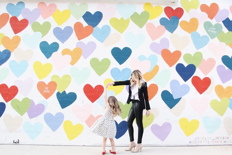 Emily and her daughter twirling at the confetti hearts wall in Charlotte.