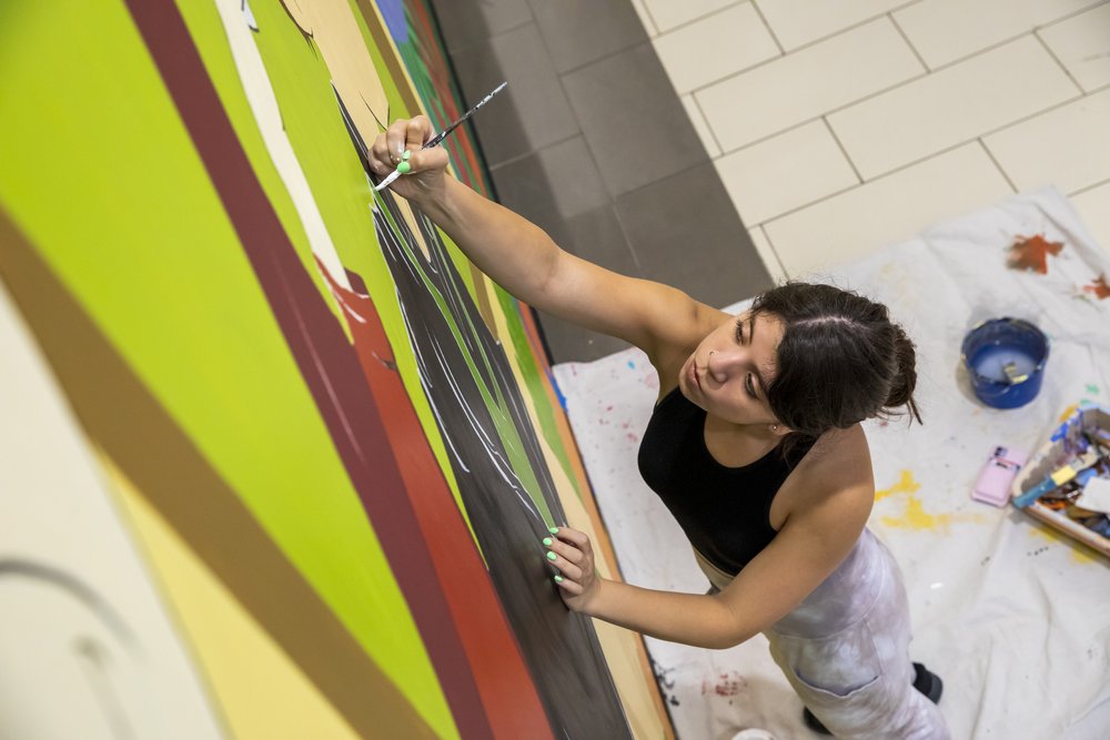  Carina Santillan, GMU Alum, paints mural at Manassas Mall. Photo by:  Sierra Guard/Creative Services/George Mason University 