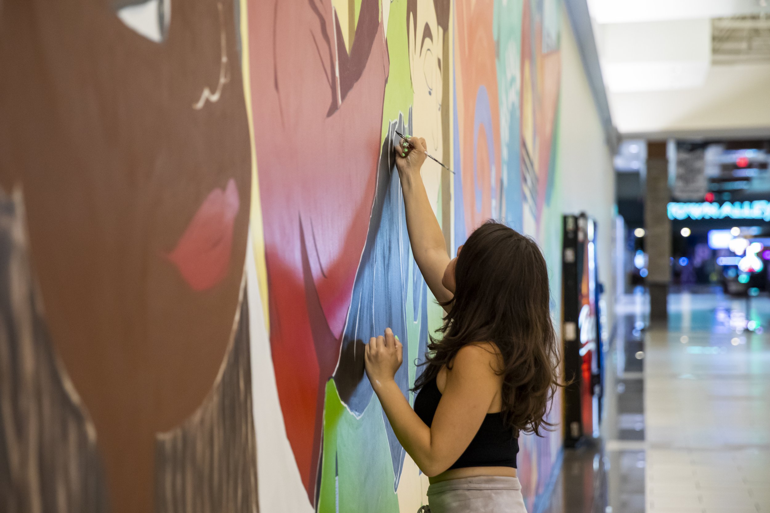  Carina Santillan, GMU Alum, paints mural at Manassas Mall. Photo by:  Sierra Guard/Creative Services/George Mason University 