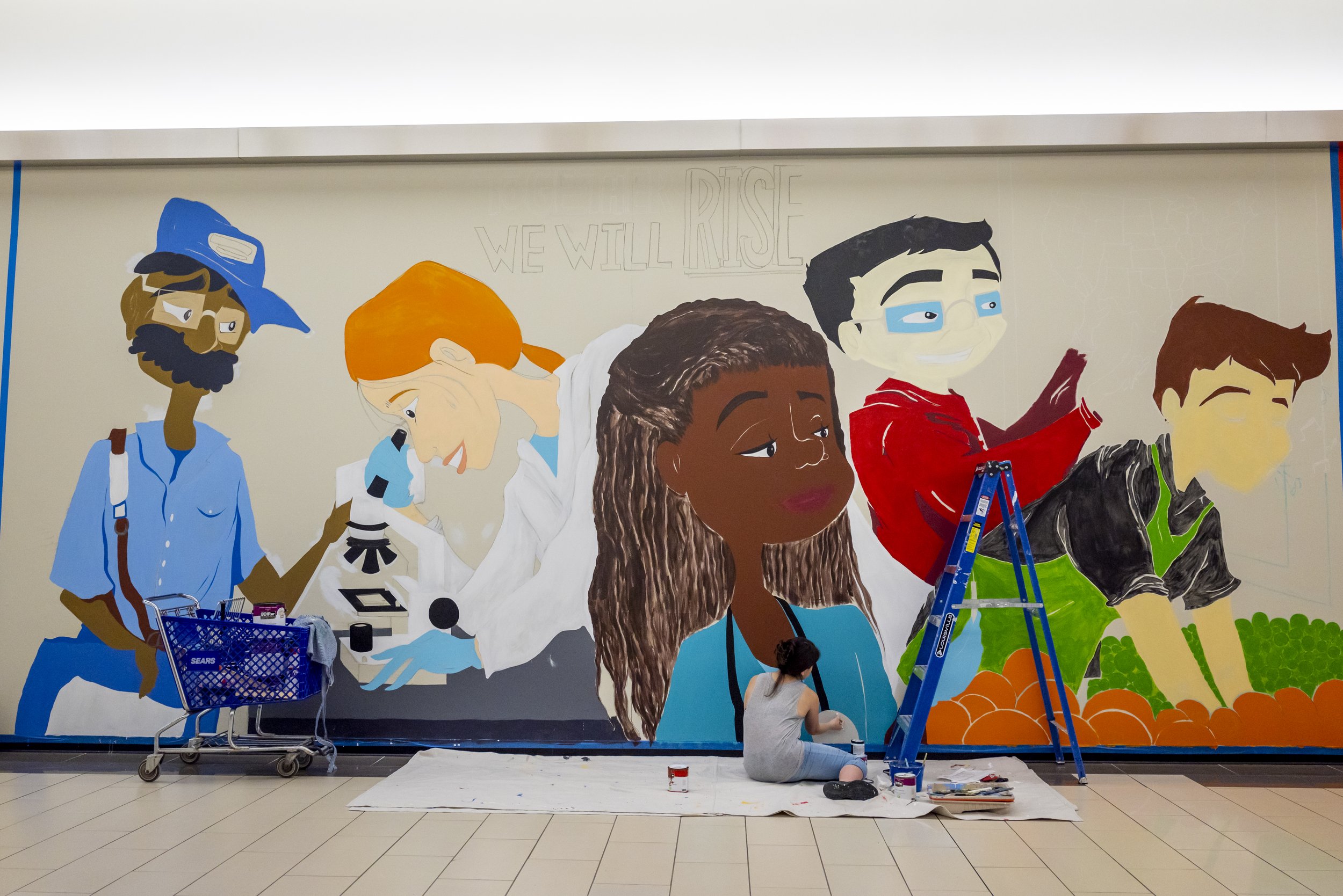  Carina Santillan, GMU Alum, paints mural at Manassas Mall. Photo by:  Sierra Guard/Creative Services/George Mason University 