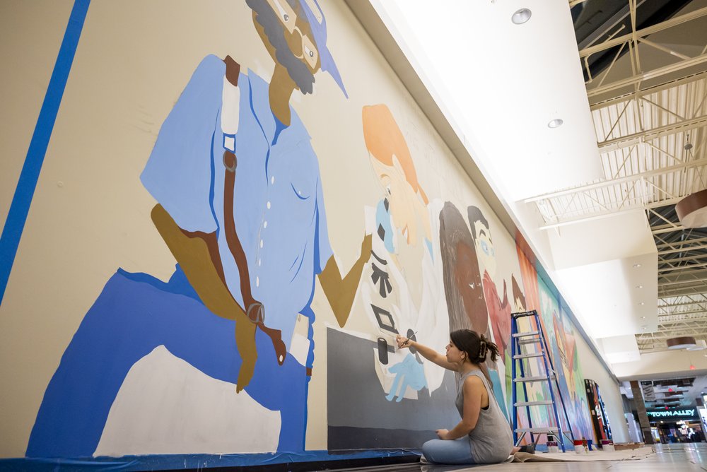 Carina Santillan, GMU Alum, paints mural at Manassas Mall. Photo by:  Sierra Guard/Creative Services/George Mason University 