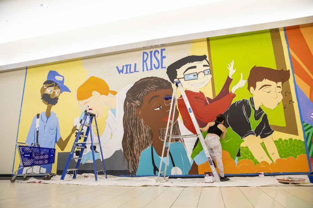  Carina Santillan, GMU Alum, paints mural at Manassas Mall. Photo by:  Sierra Guard/Creative Services/George Mason University 