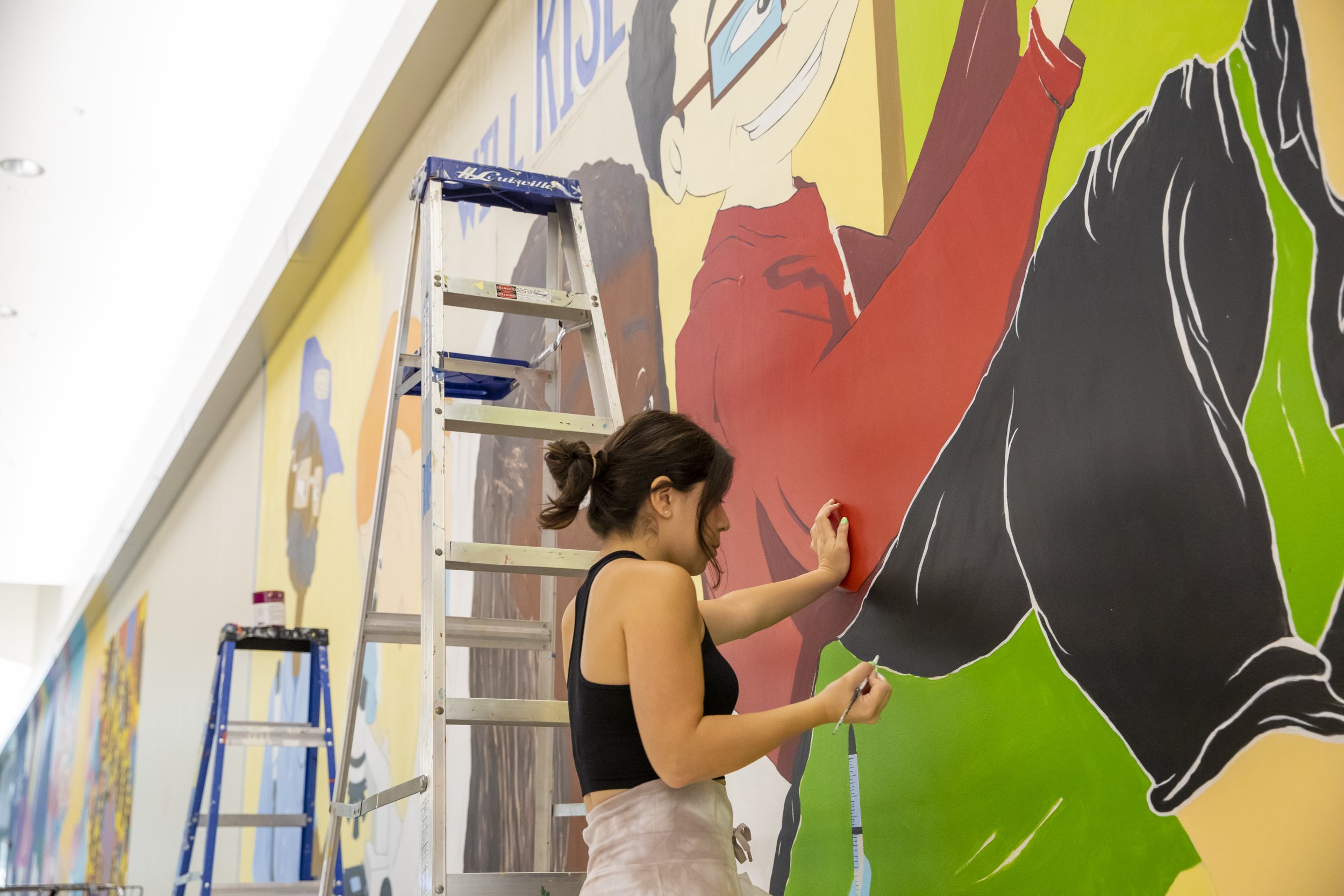  Carina Santillan, GMU Alum, paints mural at Manassas Mall. Photo by:  Sierra Guard/Creative Services/George Mason University 