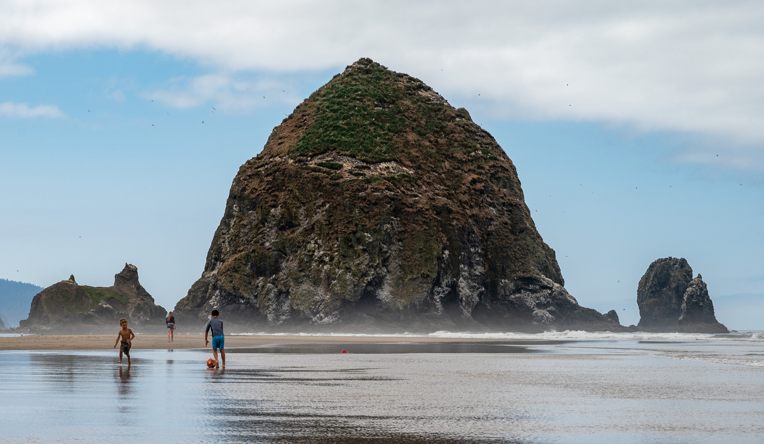  Children play soccer in front of Haystack Rock on Wednesday, Aug. 5, 2021, in Cannon Beach, Ore.  Haystack Rock is a 235-foot sea stack, known to locals as the third-tallest intertidal structure in the world. 