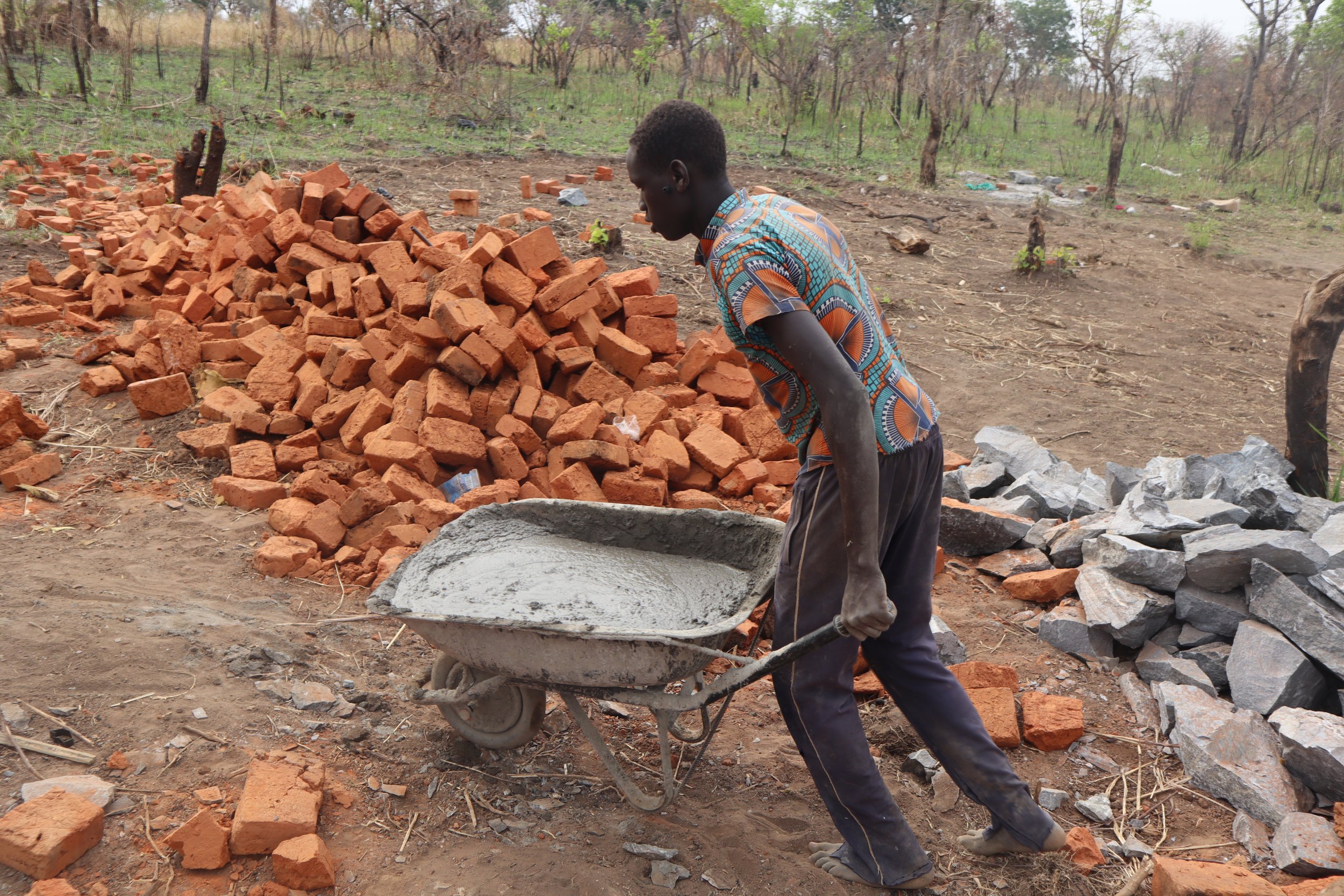 One of the porters carrying mixed cement to the house for the foundation to be casted