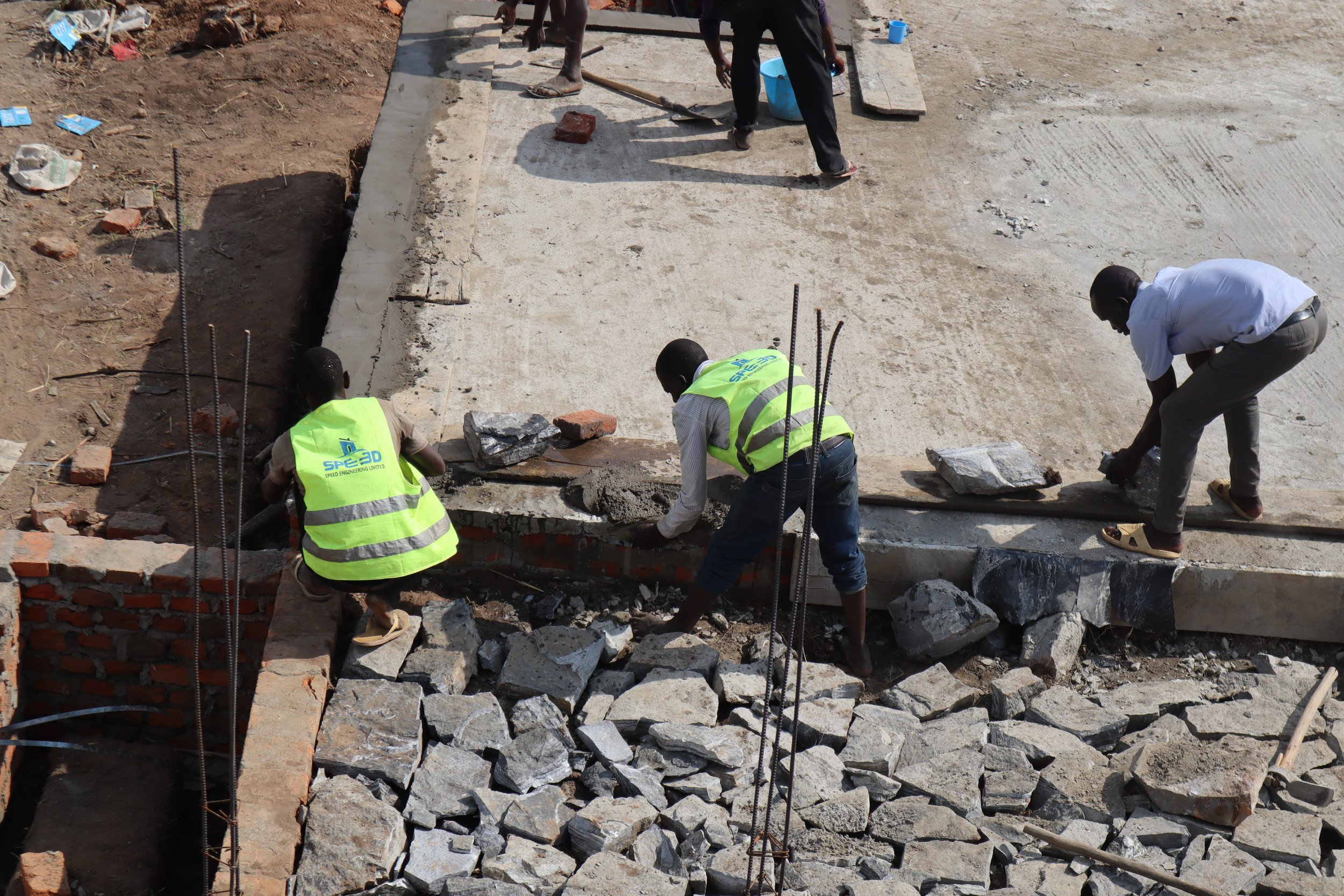 Site builders laying hardcore rocks to ensure a strong foundation prior to casting the main veranda