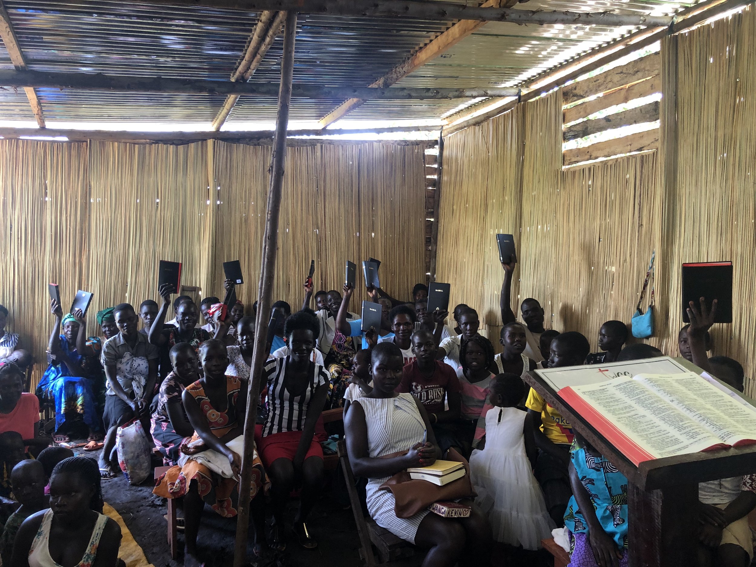 Congregants at The Word Community Church holding up Acholi Bibles during the distribution