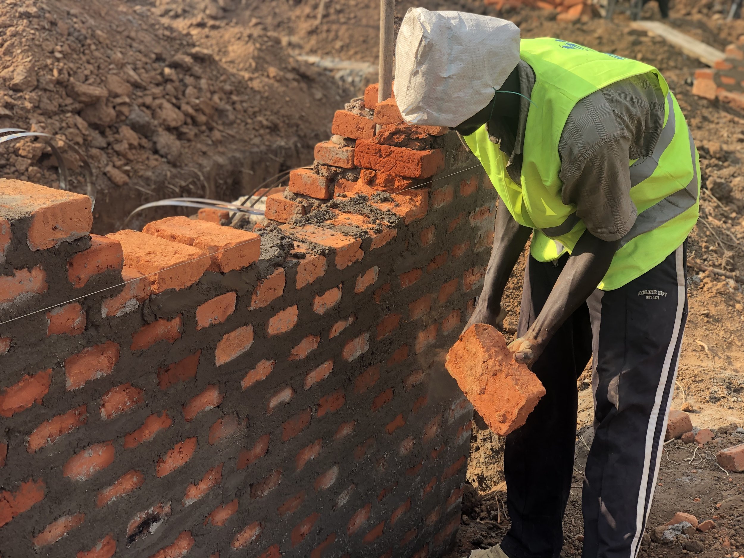 A builder laying bricks for the house's foundation