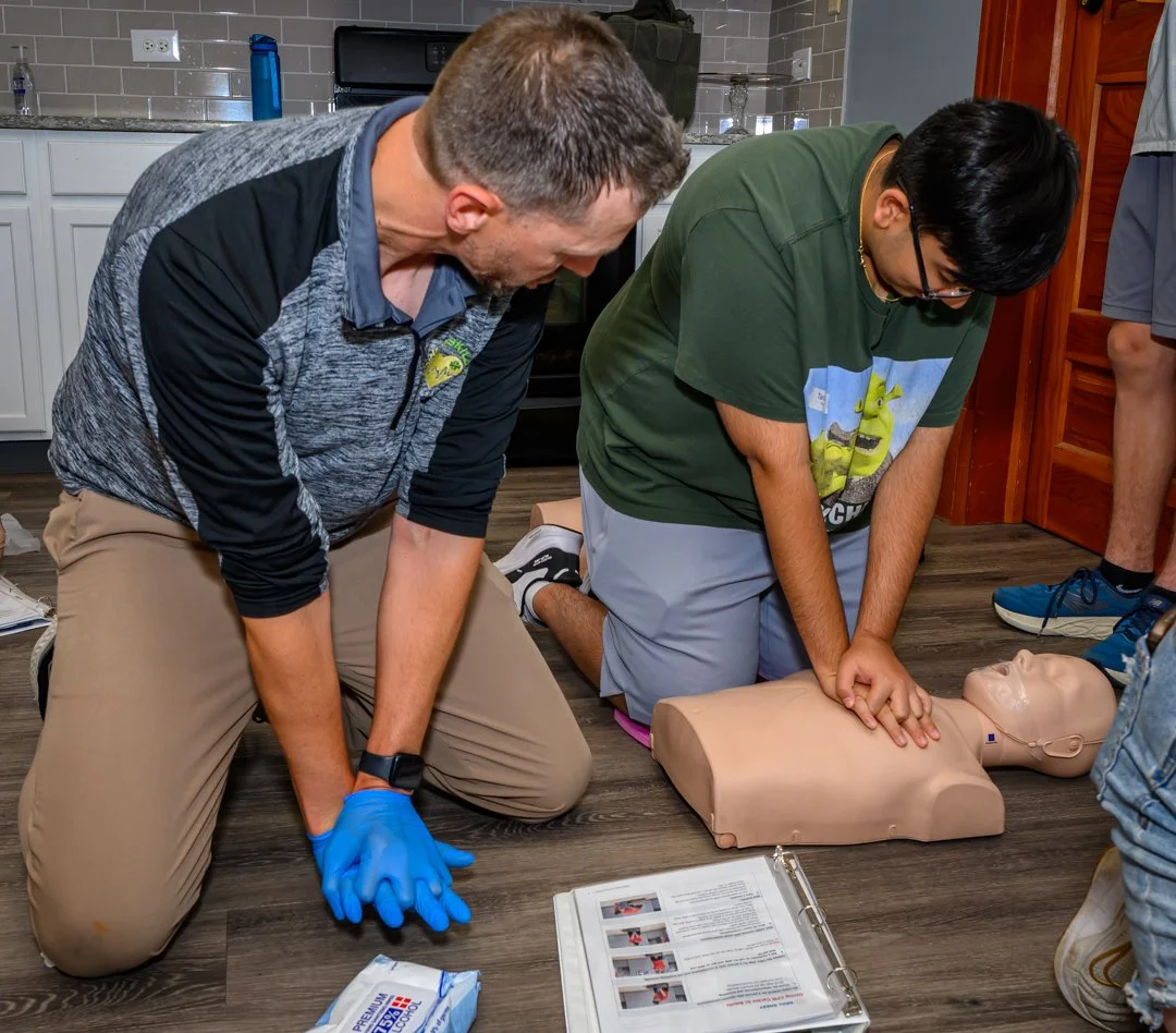 Bobby Dobroski of DobroSKILLS assists student with performing chest compressions on CPR manikin