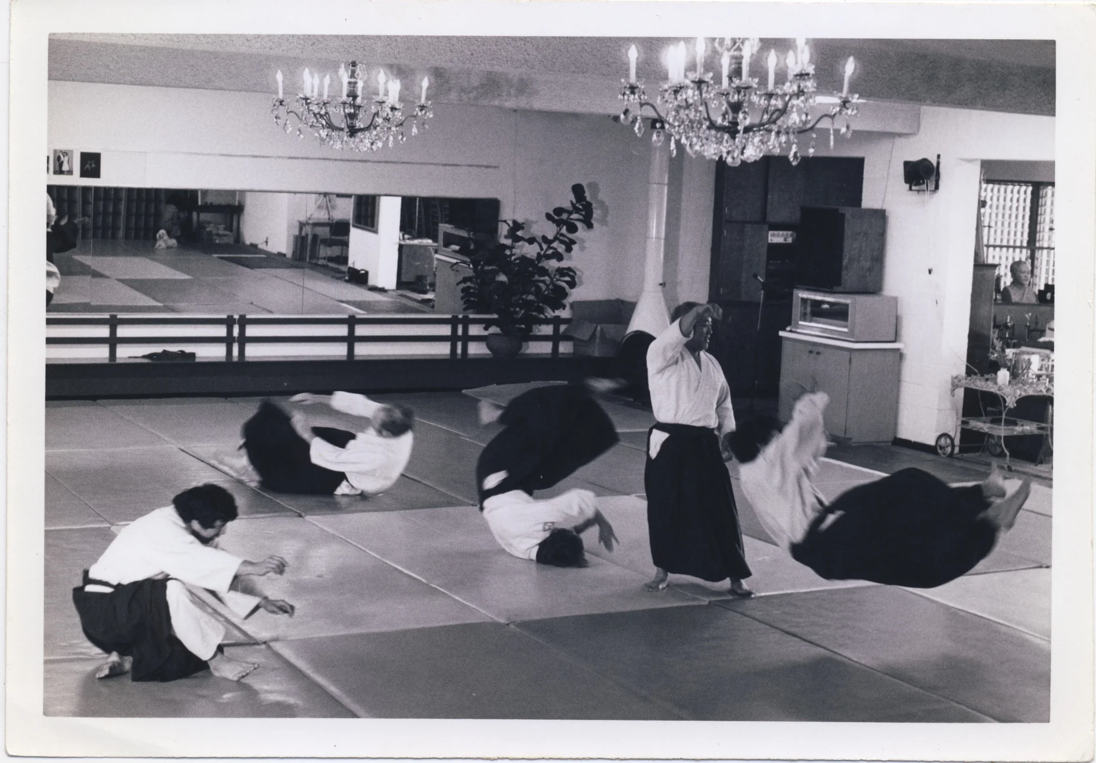 Sensei demonstrates a throw with the help of four black belts under the famous chandelier.