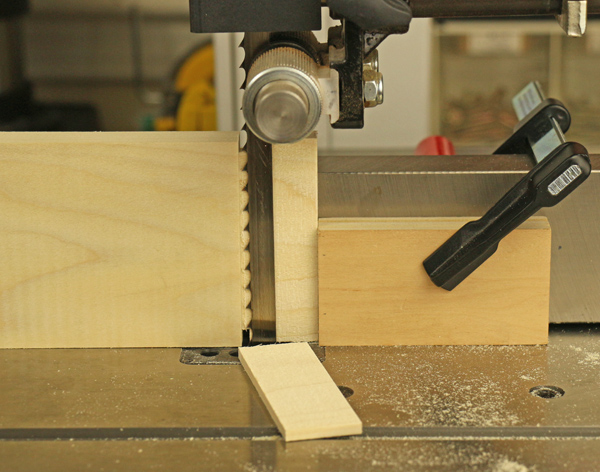 A typical band saw operation that requires an operator to retrieve the material while the machine may still be coasting.