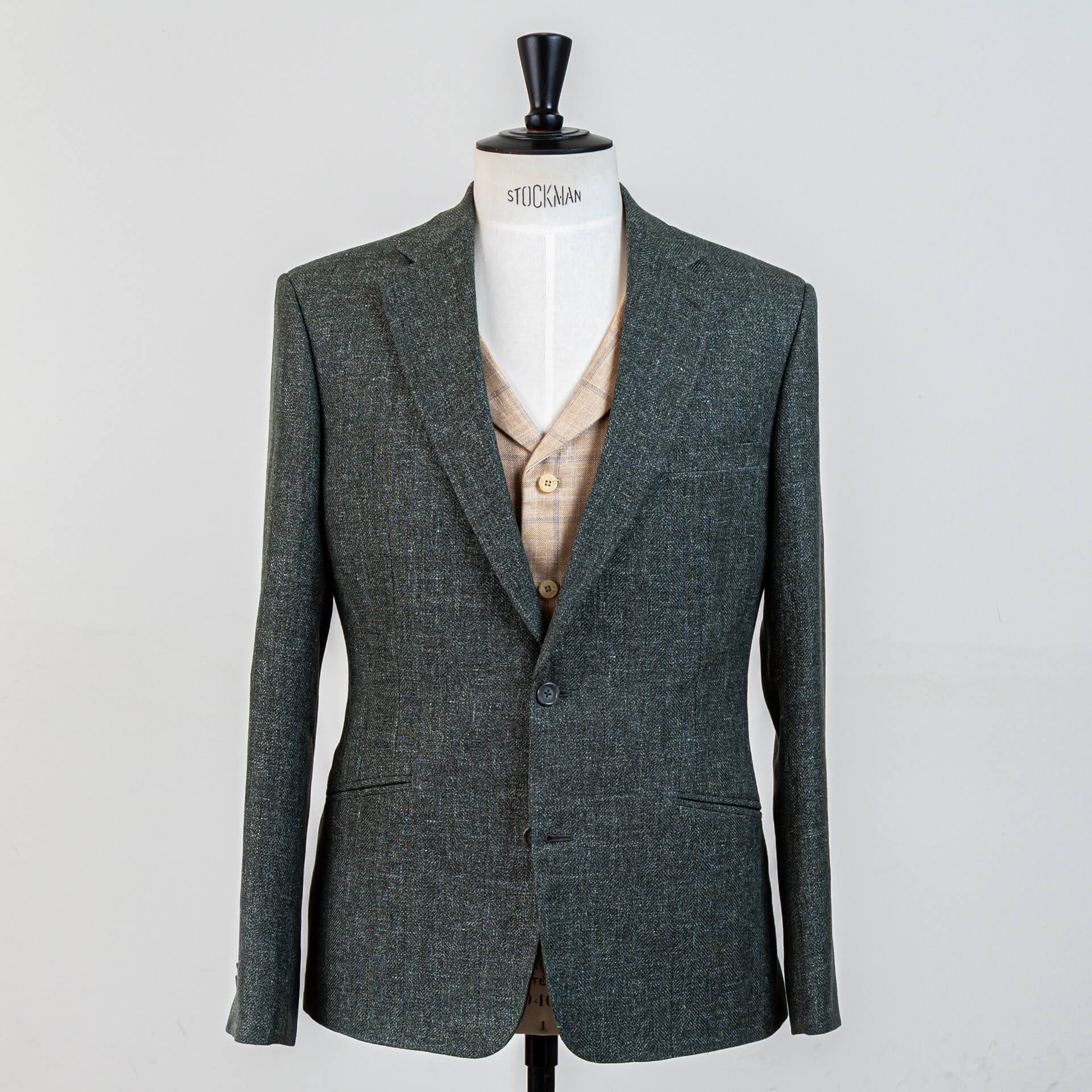 Vooraanzicht groen bespoke trouwpak met gesloten 2-knoops colbert en zandkleurig contrast gilet. Wol-linnen-zijde stof van Piacenza 1733 voor natuurlijke uitstraling op zomerbruiloften.