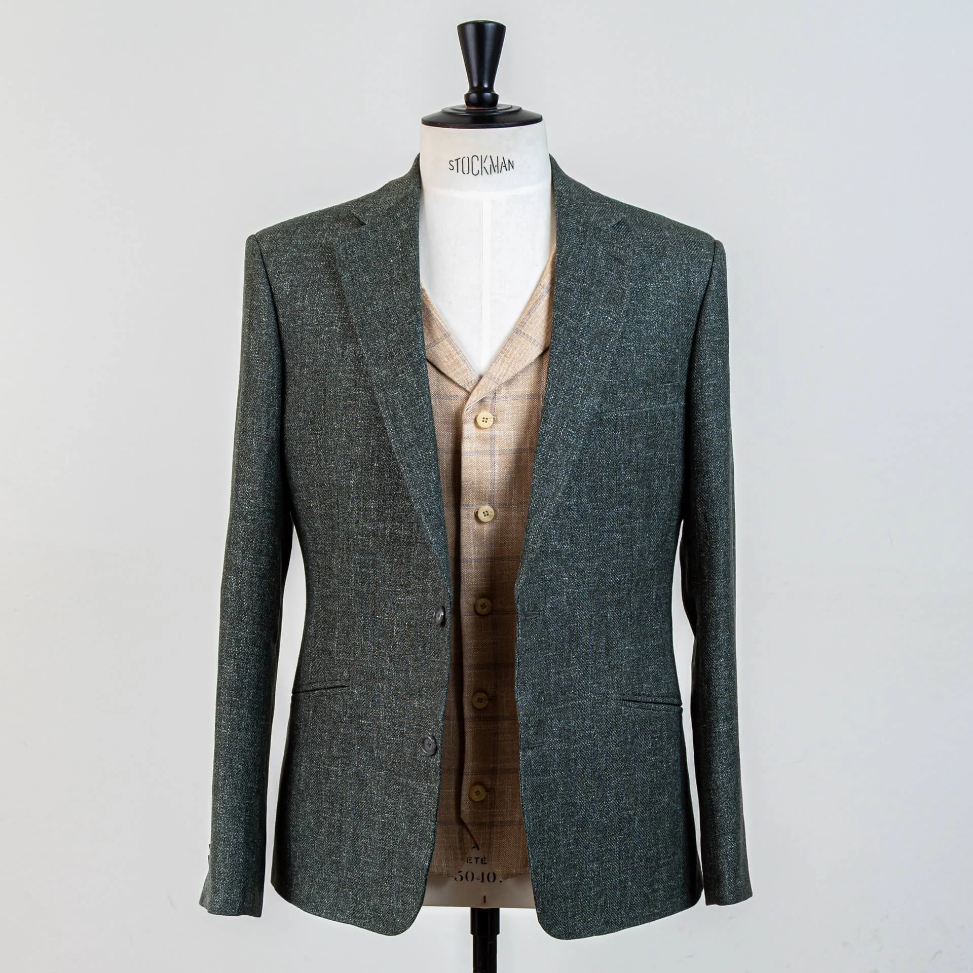 Volledig vooraanzicht 3-delig groen trouwpak op maat met open colbert en zandkleurig gilet met blauw ruitpatroon. Ideale combinatie voor Bohemian en garden bruiloften.