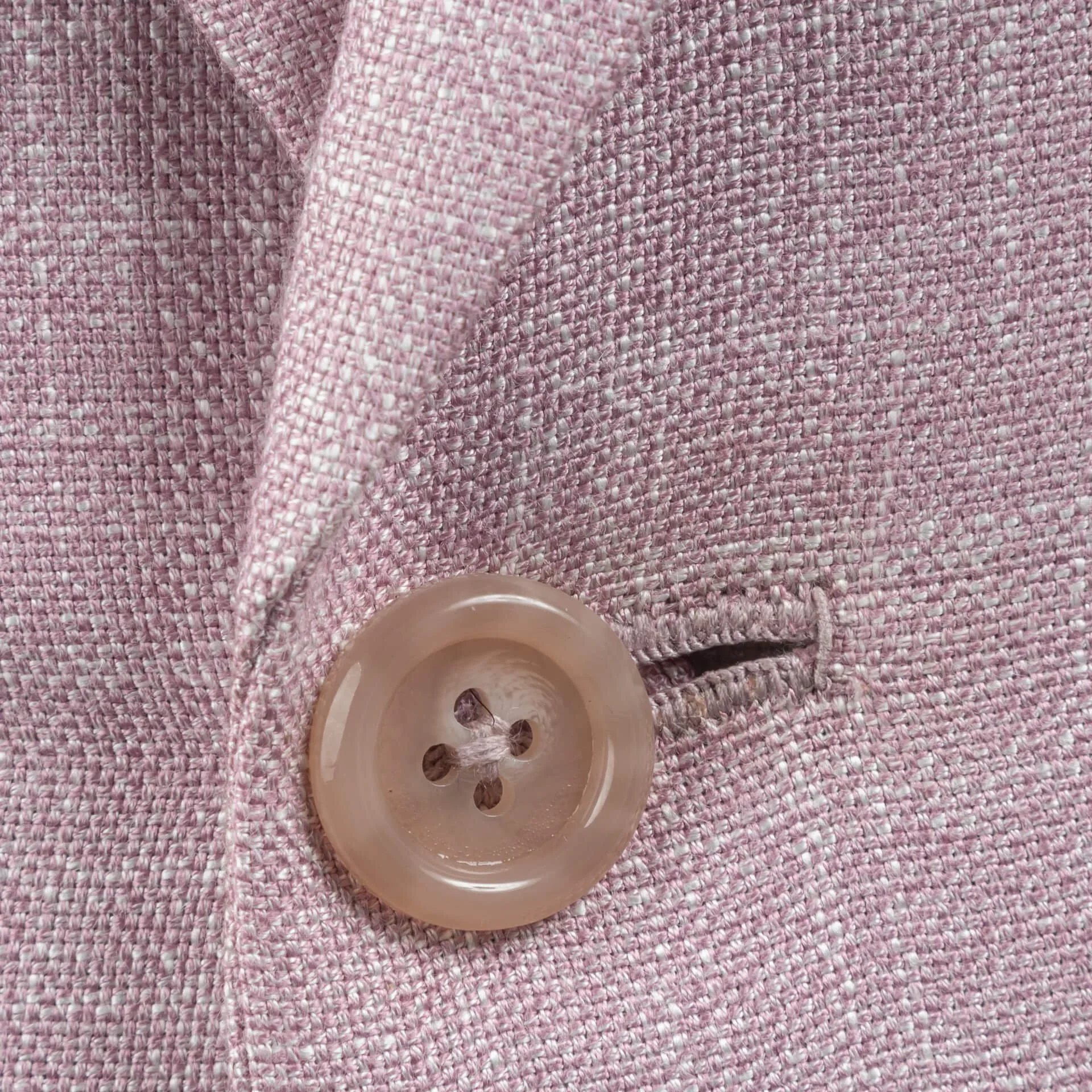 Close-up van natuurkleurige knoop met handgenaaid knoopsgat op roze bamboe colbert