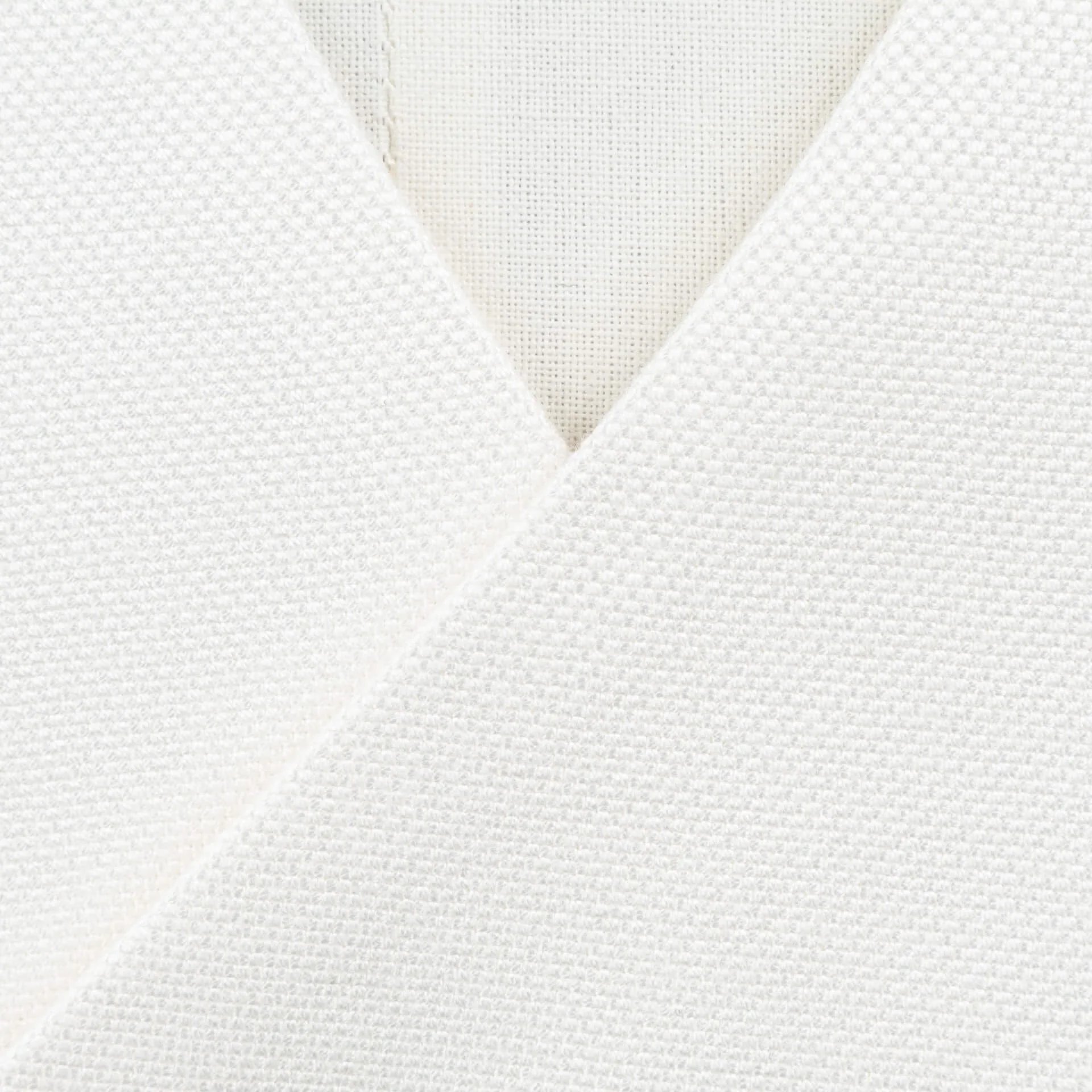 Close-up van V-hals en asymmetrische sluiting op wit bespoke trouwgilet met zichtbare stofstructuur