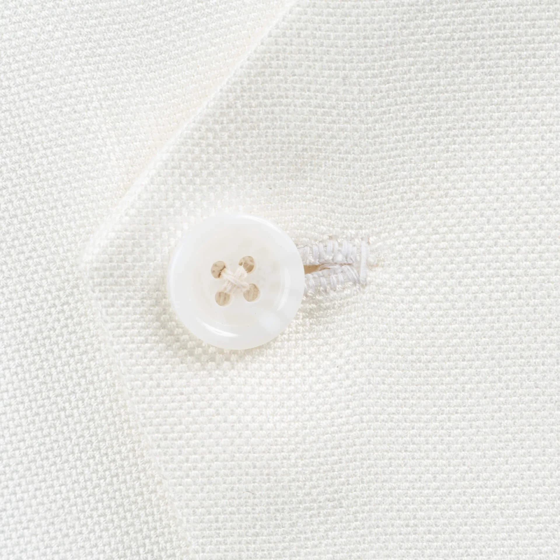 Close-up van witte knoop met handgenaaid knoopsgat op asymmetrisch trouwgilet